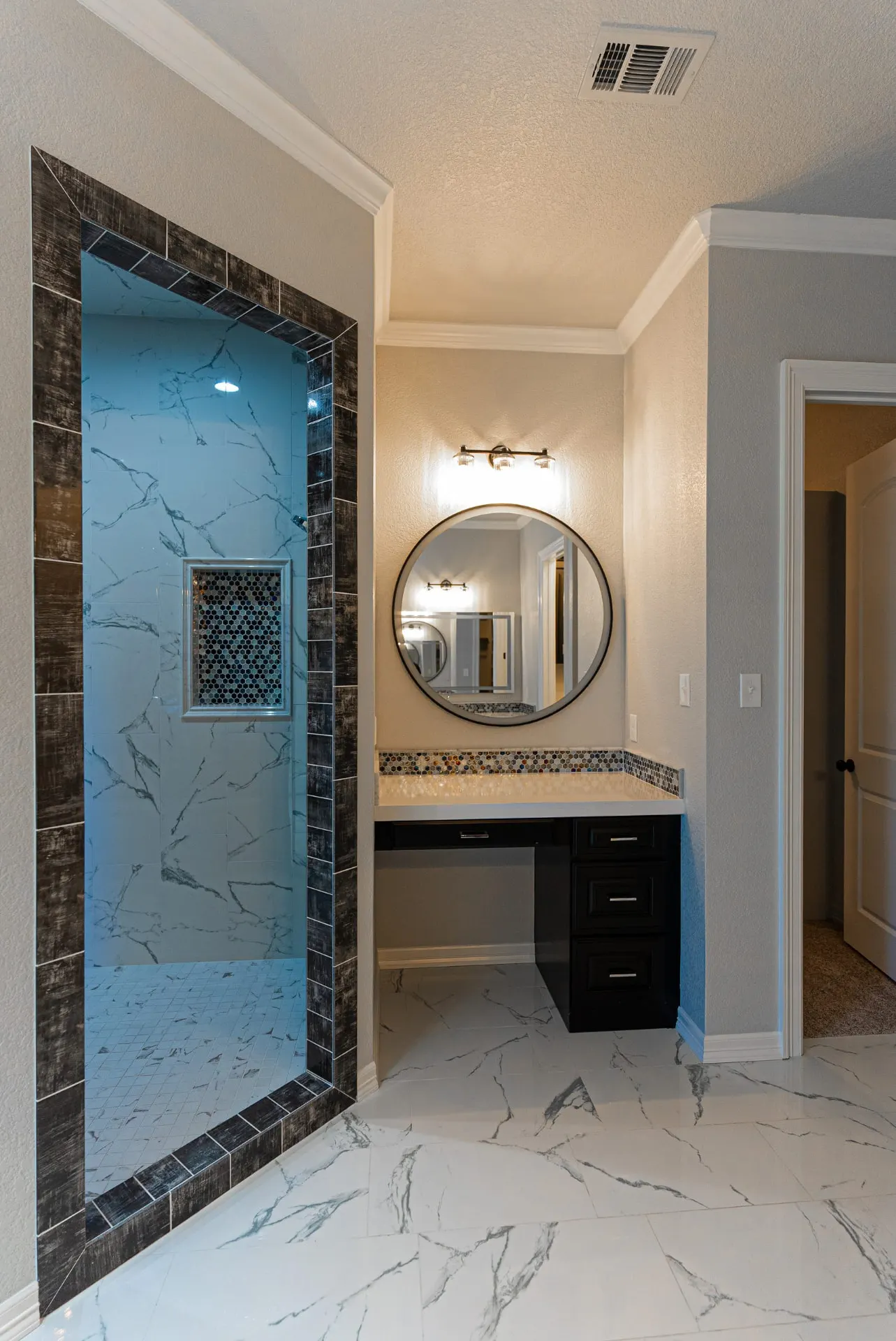 Bathroom at 1511 NW 12th St with glass-enclosed marble shower, round mirror and black makeup vanity