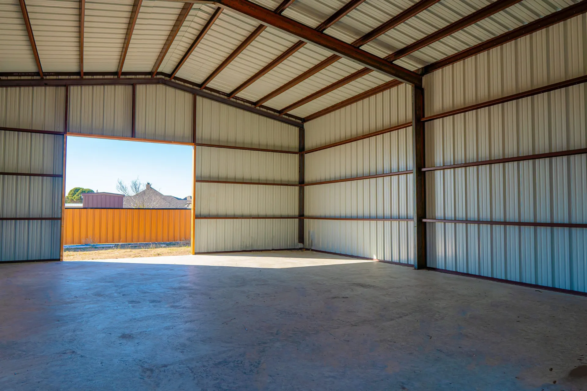 Interior of the metal shop at 8821 Shawn Dr with clear-span steel framing, insulated walls and an open drive-through bay