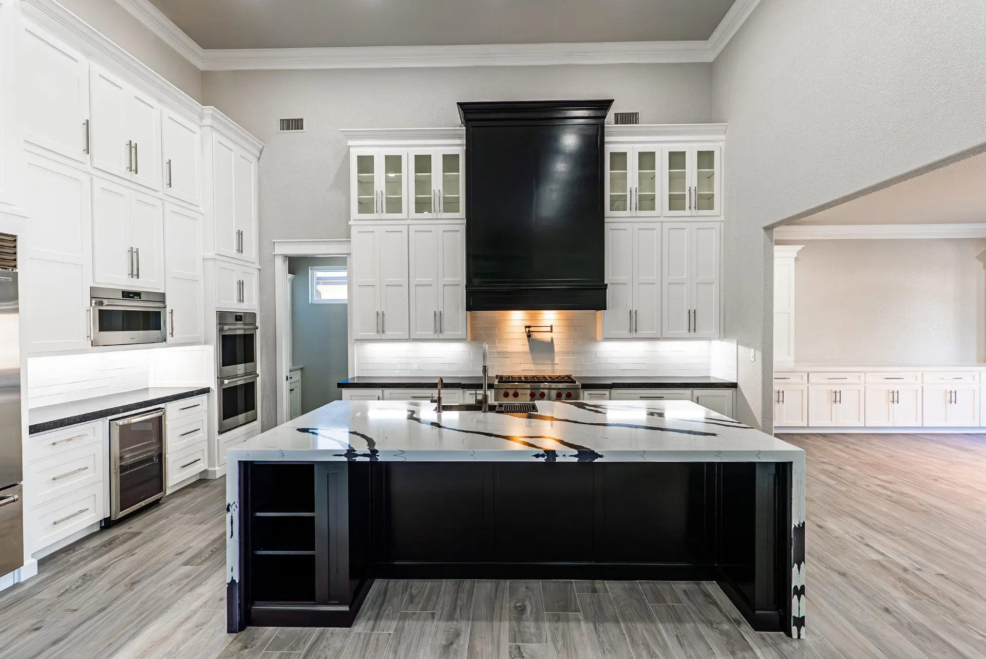 Kitchen at 27 Santiago Mission Dr with a black range hood, white shaker cabinetry and a waterfall island in white-and-black veined quartz