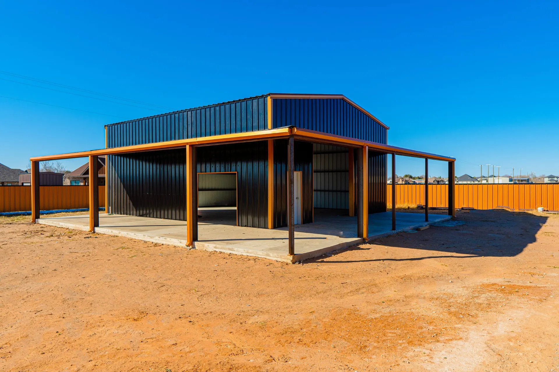 Black-and-copper metal shop with wraparound covered lean-tos on a concrete slab at 8821 Shawn Dr