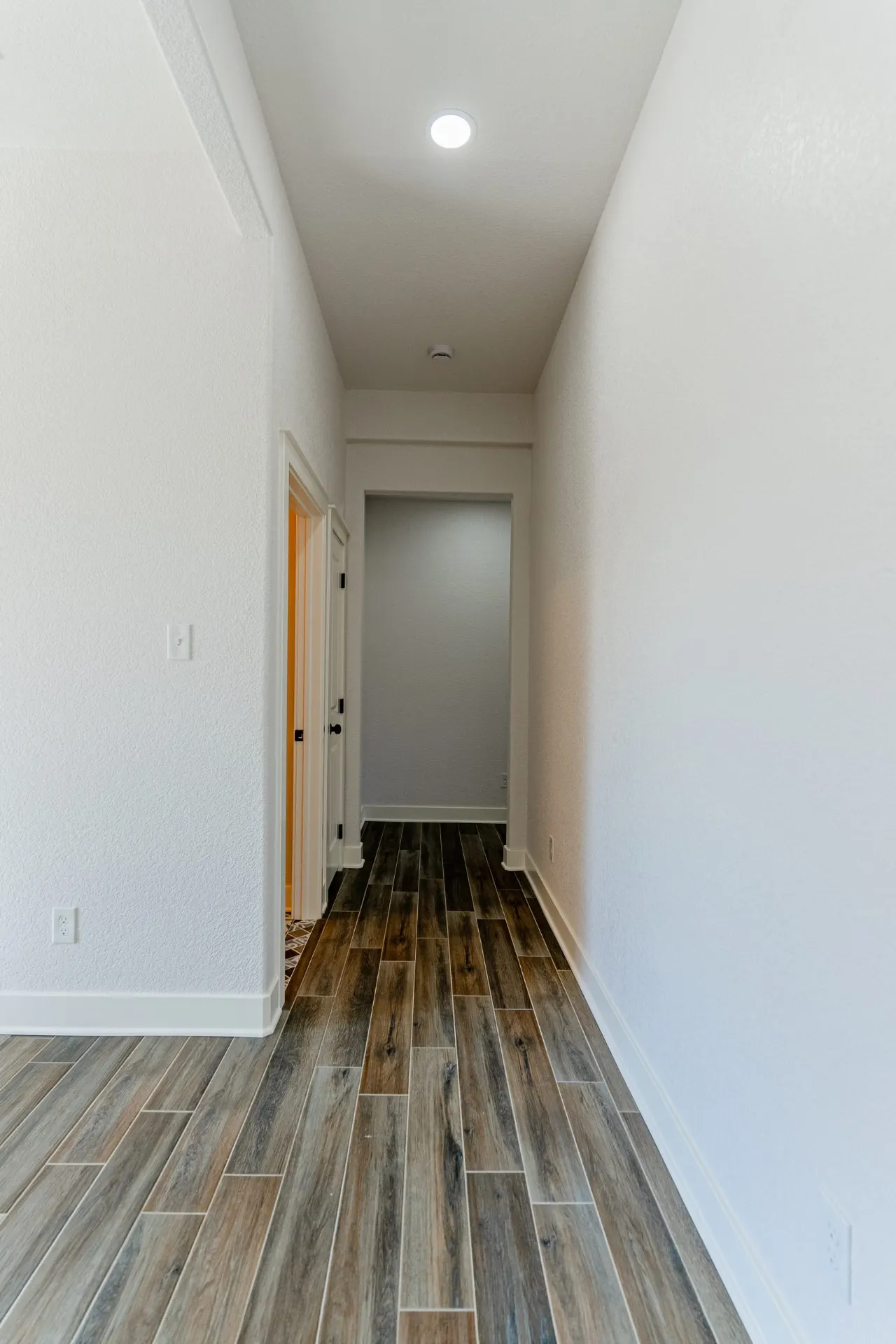 Hallway at 718 K Ave with crisp white walls and honey-toned wood-look floors leading toward the bedrooms
