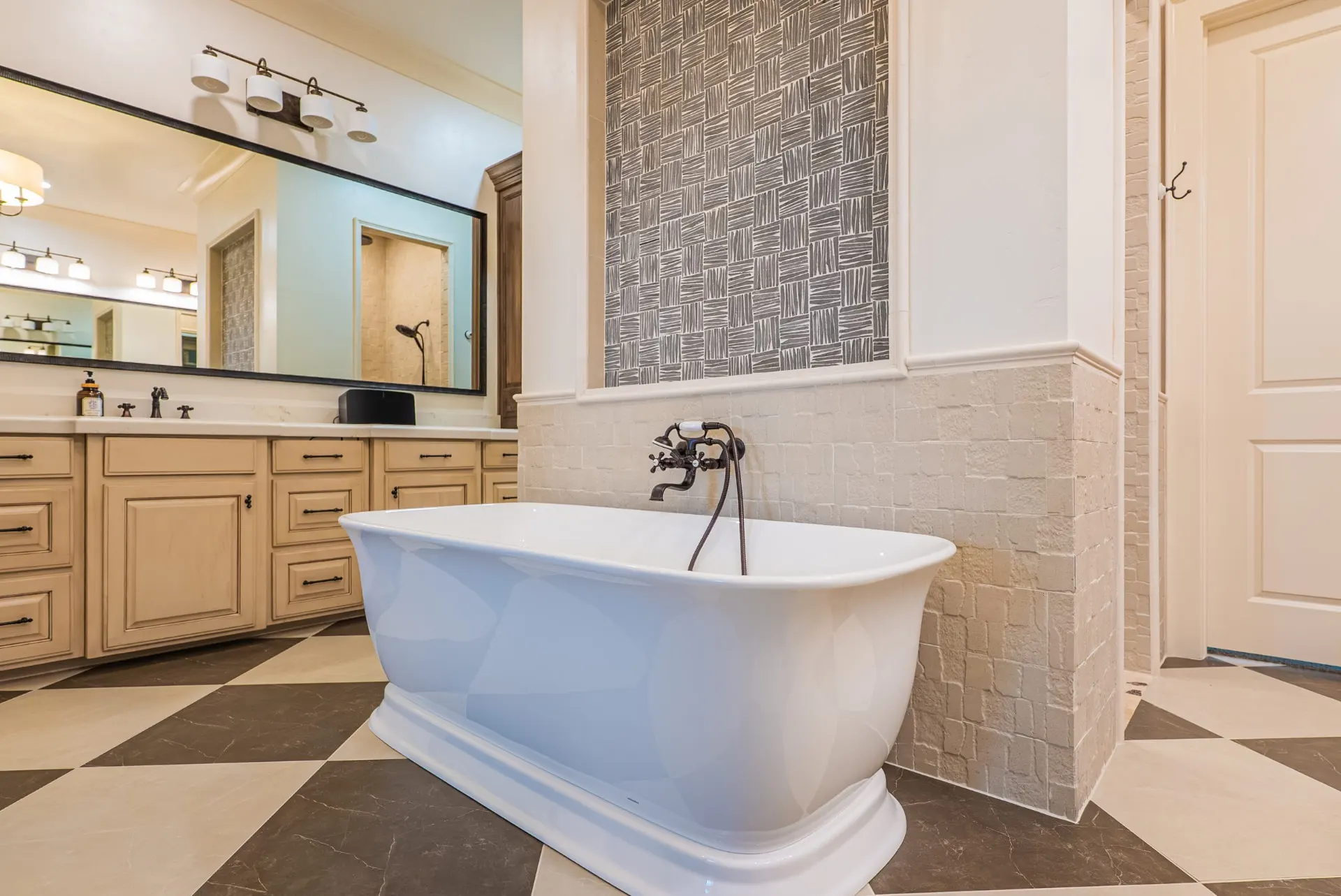Freestanding tub at 1610 NW Eliam Dr set against a patterned tile panel, with checkerboard stone floors