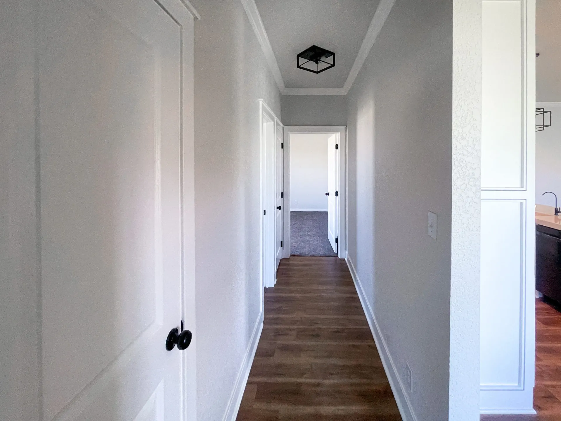 Hallway at 1615 NW 12th St with coffered ceiling detail, black flush light, paneled doors and wood-look floors