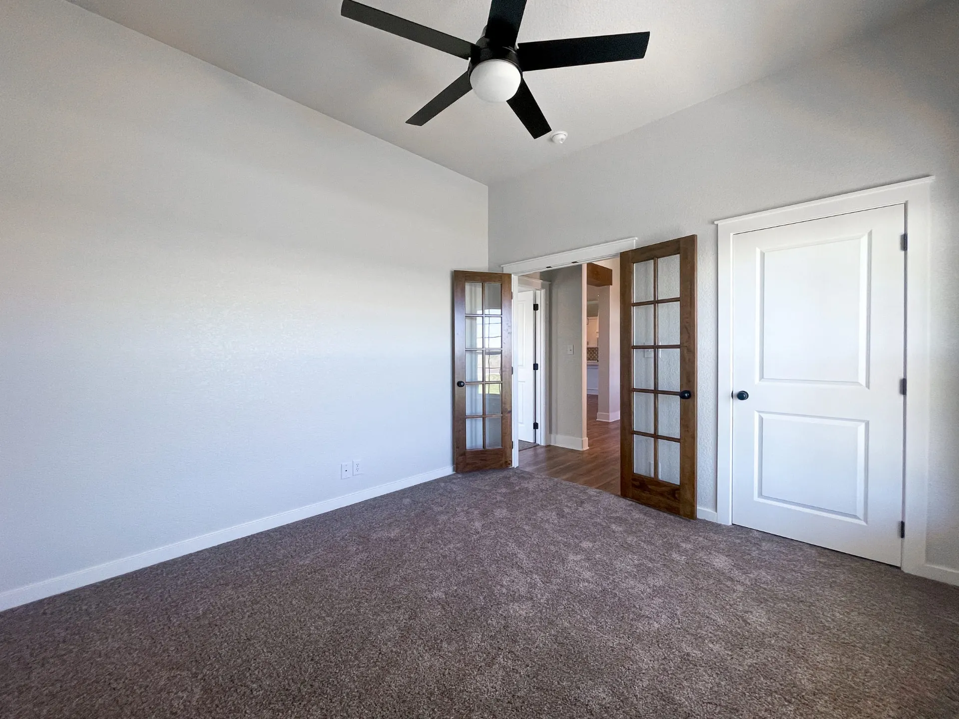 Bedroom at 1615 NW 12th St with carpeted floors, black ceiling fan, glass-paneled double doors and white trim