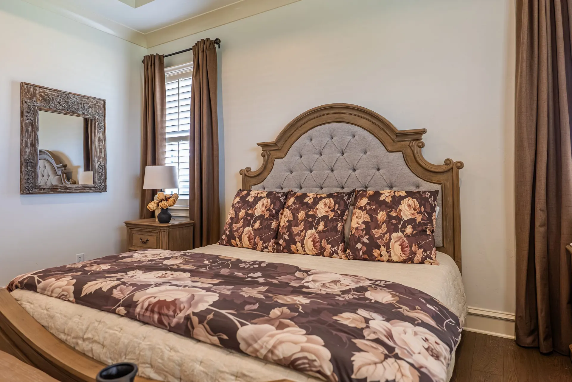 Bedroom at 1610 NW Eliam Dr with arched tufted headboard, plantation shutters and wood floors