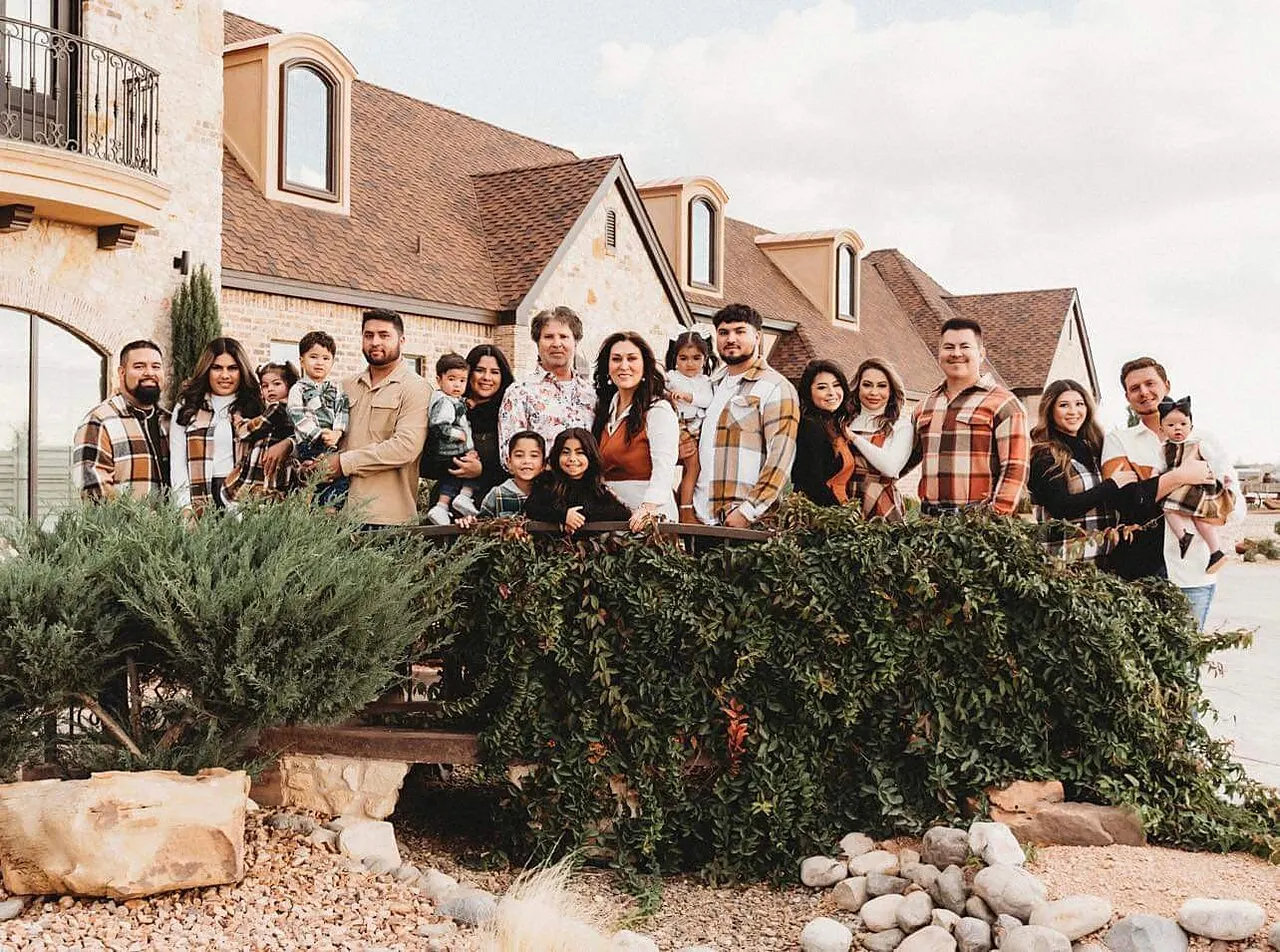 The Flores family, three generations, standing together in front of the stone estate home Saul Flores built in Andrews, Texas.