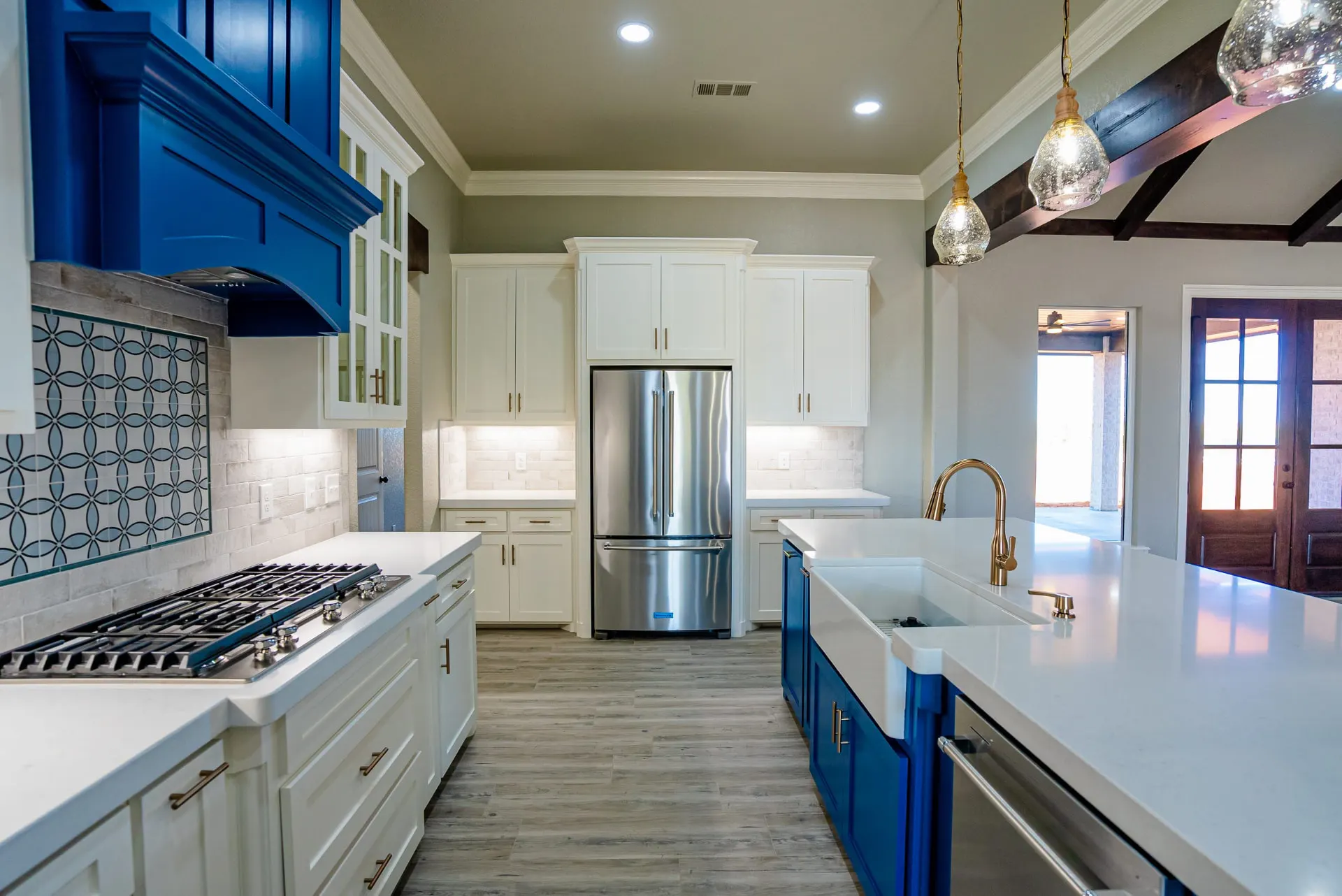 Eliam St Home kitchen looking down the galley to the refrigerator wall, with the cobalt island farmhouse sink and brass faucet in the foreground