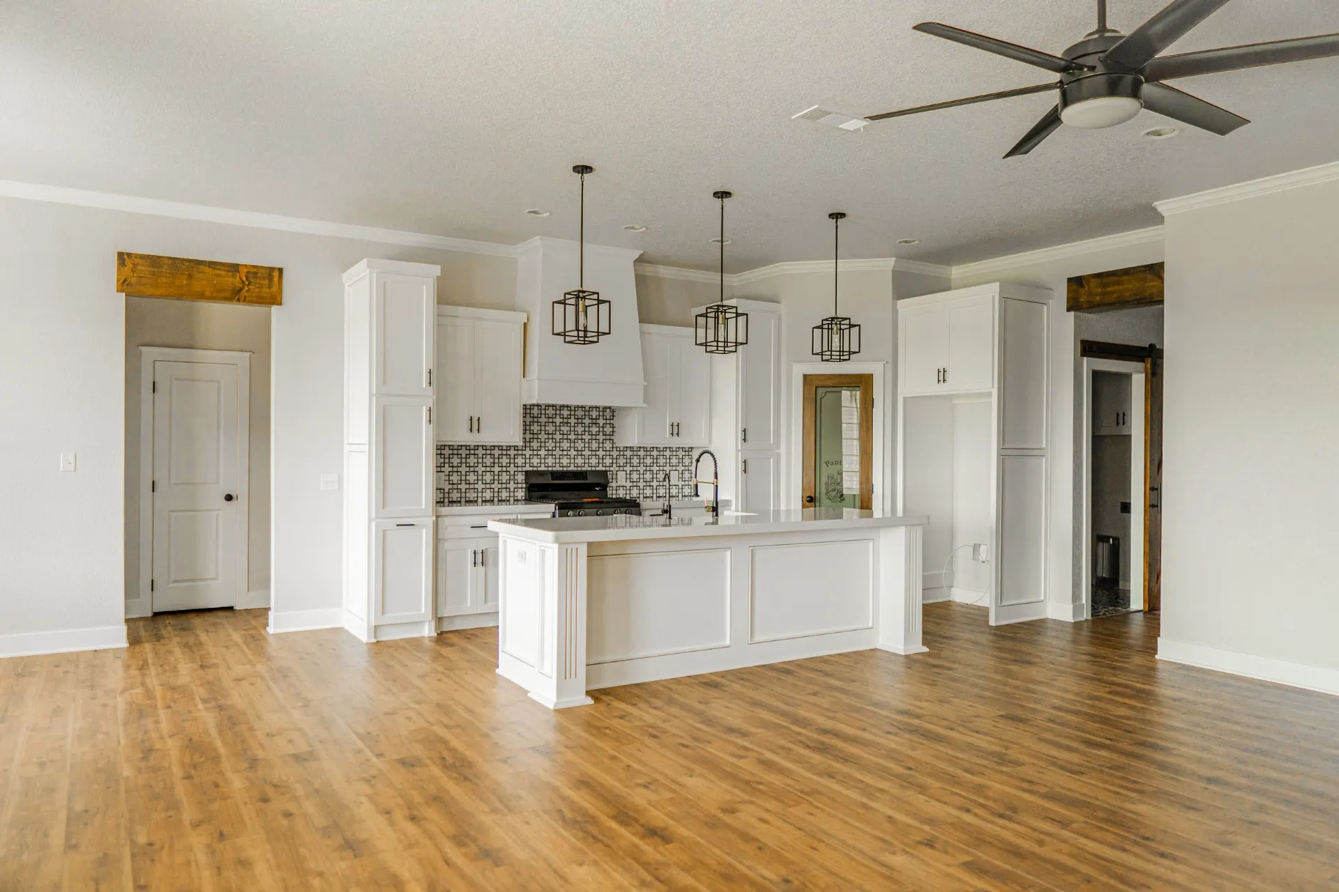 Kitchen and living space at 1615 NW 12th St with paneled island, stained wood lintels and pantry door