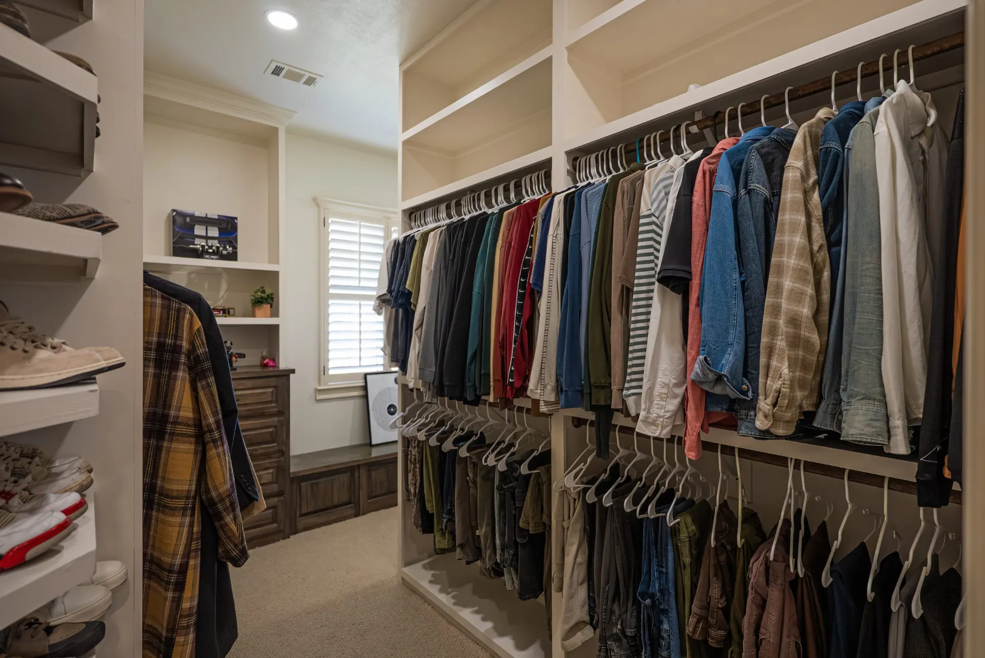 Primary walk-in closet at 1610 NW Eliam Dr with double hanging rods, built-in dresser and window seat