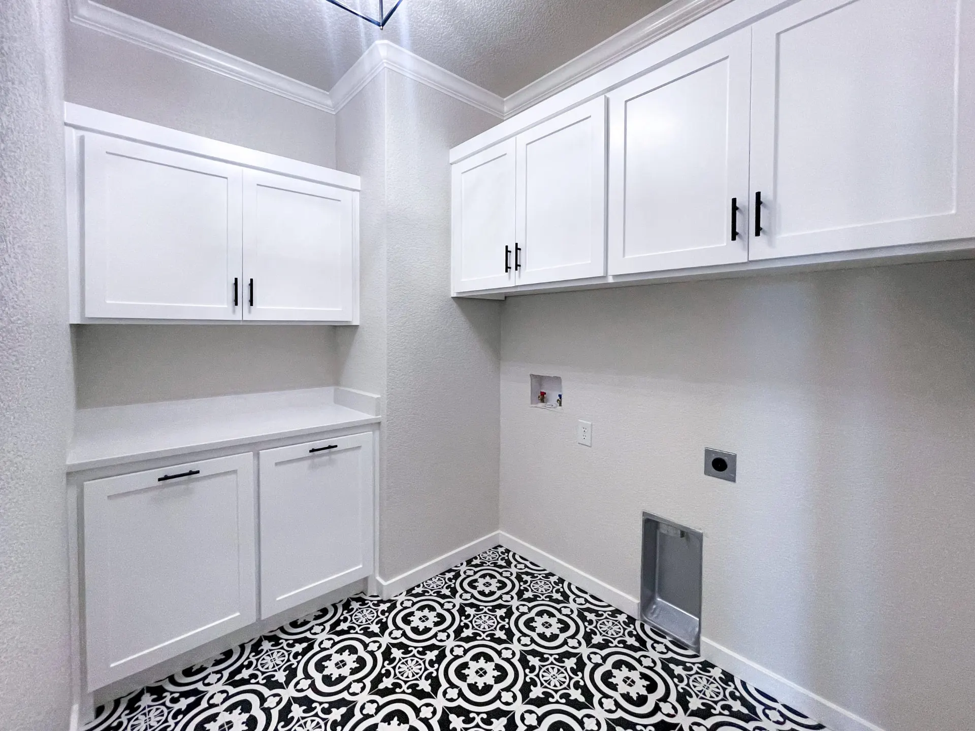 Laundry room at 1615 NW 12th St with white cabinets, patterned black-and-white floor tile and ironing niche