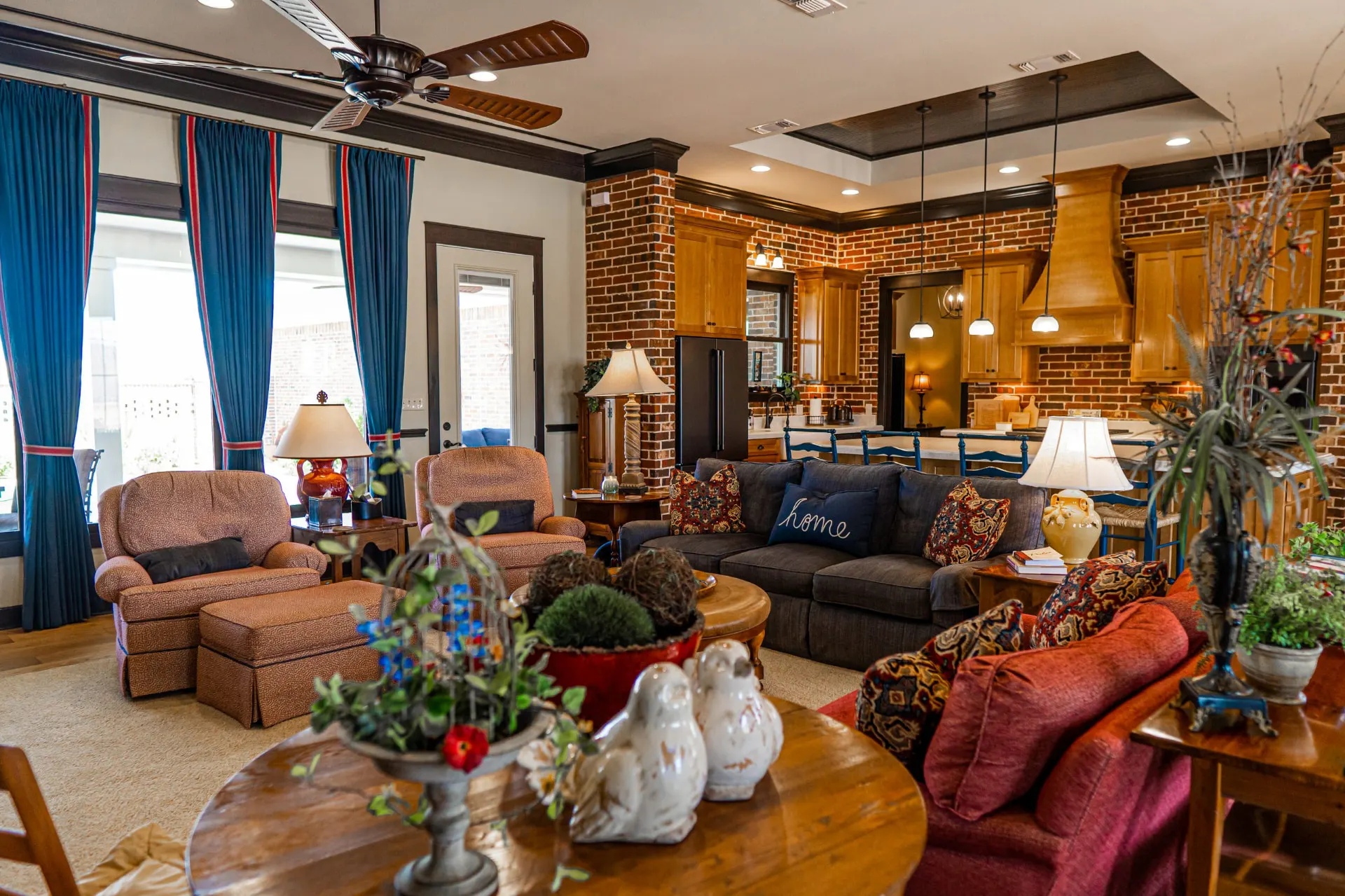 Great room at the Wraparound Porch Home opening to the kitchen, with brick walls, a wood range hood and pendant lights