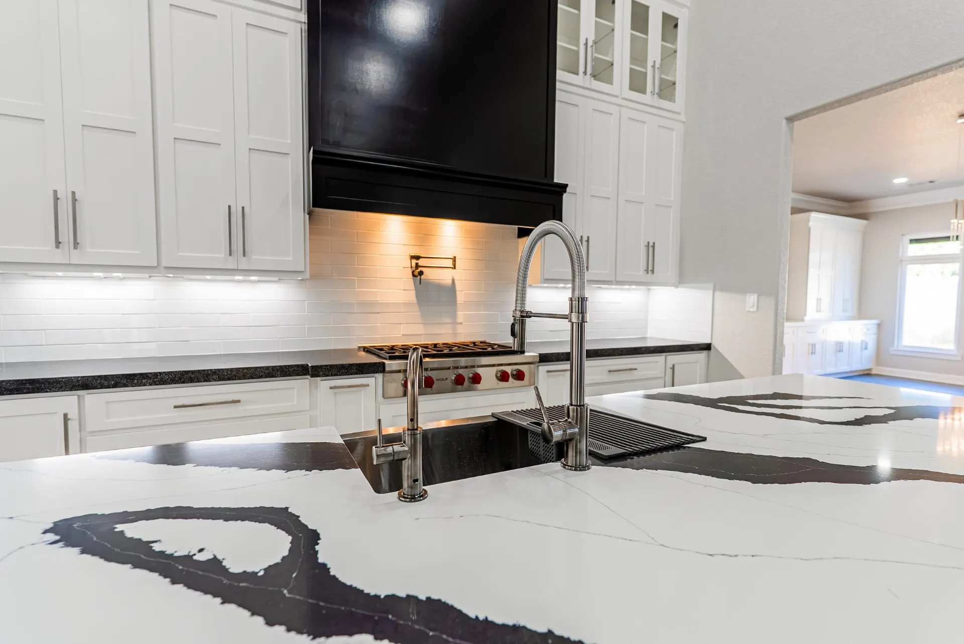 Detail of the 27 Santiago Mission Dr island: veined quartz, a pull-down faucet and a black hood above the rangetop