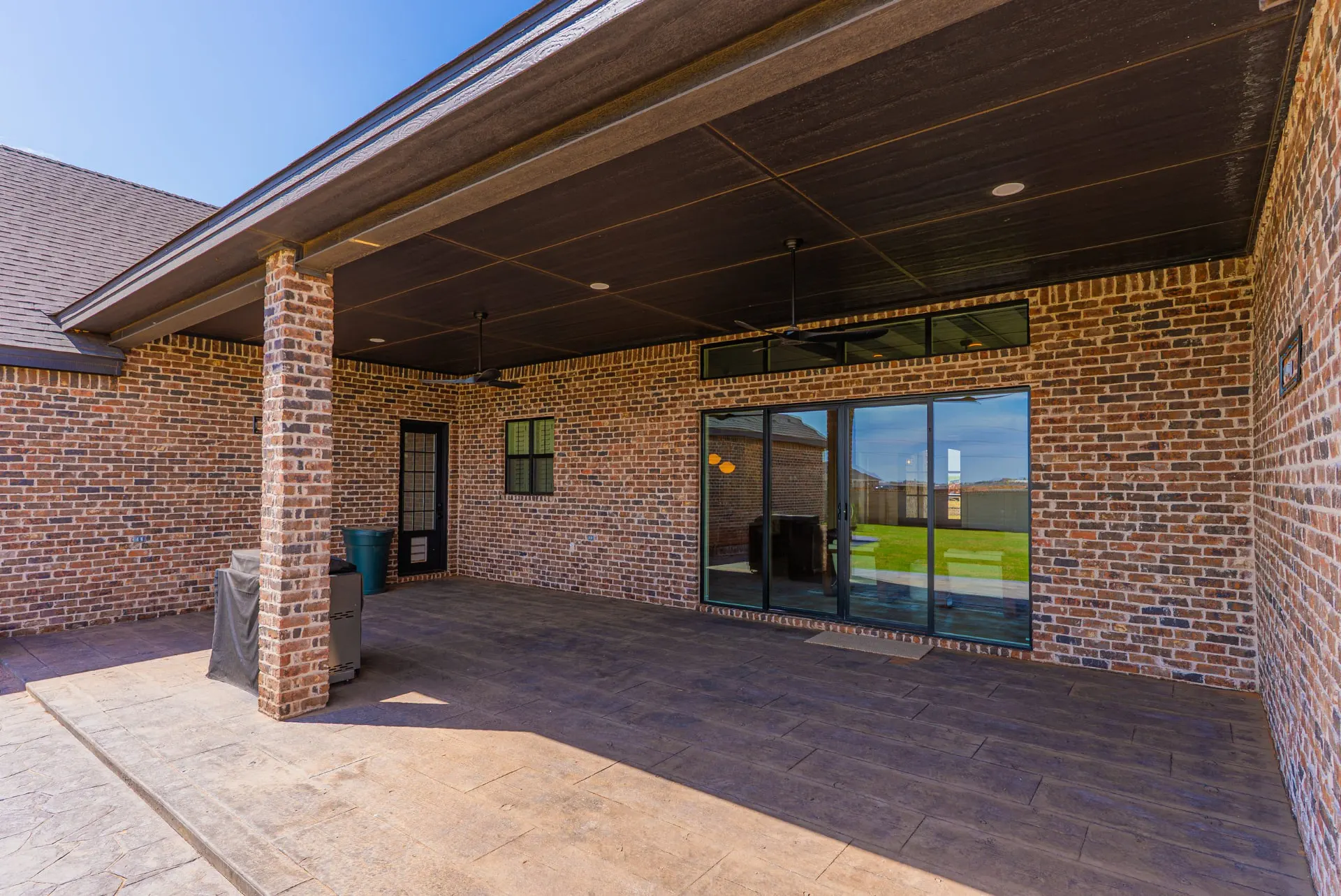 Covered back patio at 1610 NW Eliam Dr with stamped concrete floors, a dark wood ceiling and ceiling fans
