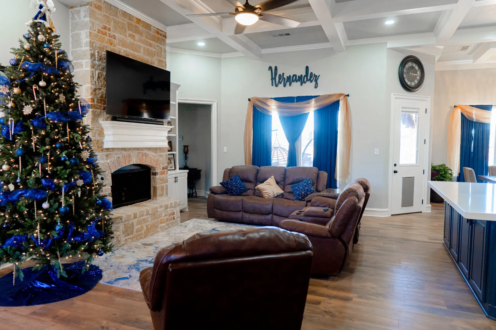 Great room at 8821 Shawn Dr with a stacked-stone fireplace and white mantel, a coffered ceiling and the navy kitchen island at the edge