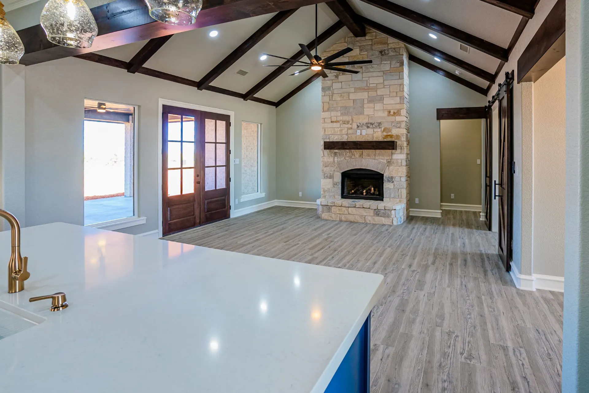Great room at the Eliam St Home seen from the kitchen, with the stone fireplace, dark-stained French doors and stained-glass sidelights