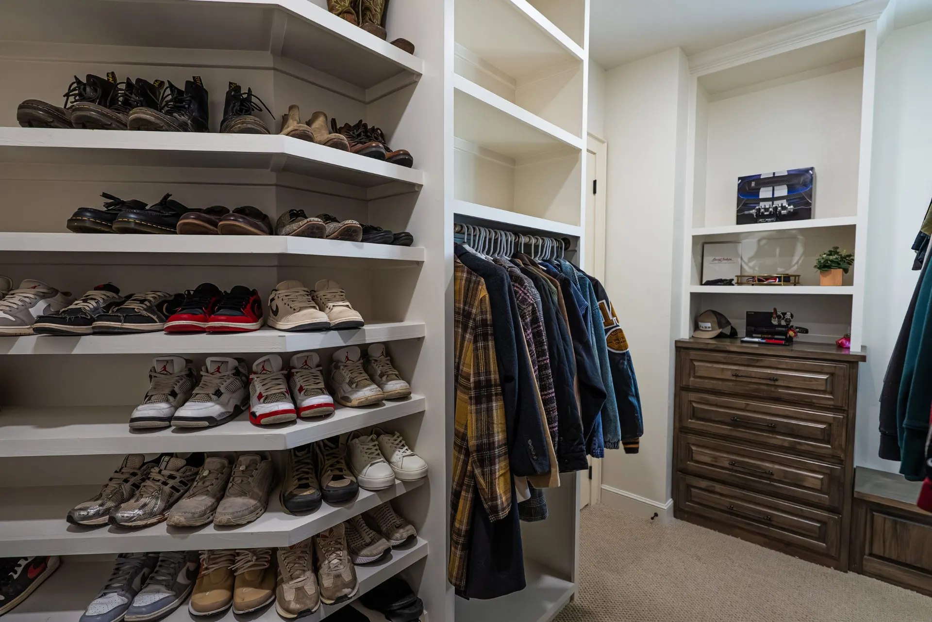 Primary closet at 1610 NW Eliam Dr with floor-to-ceiling shoe shelving and stained built-in drawers