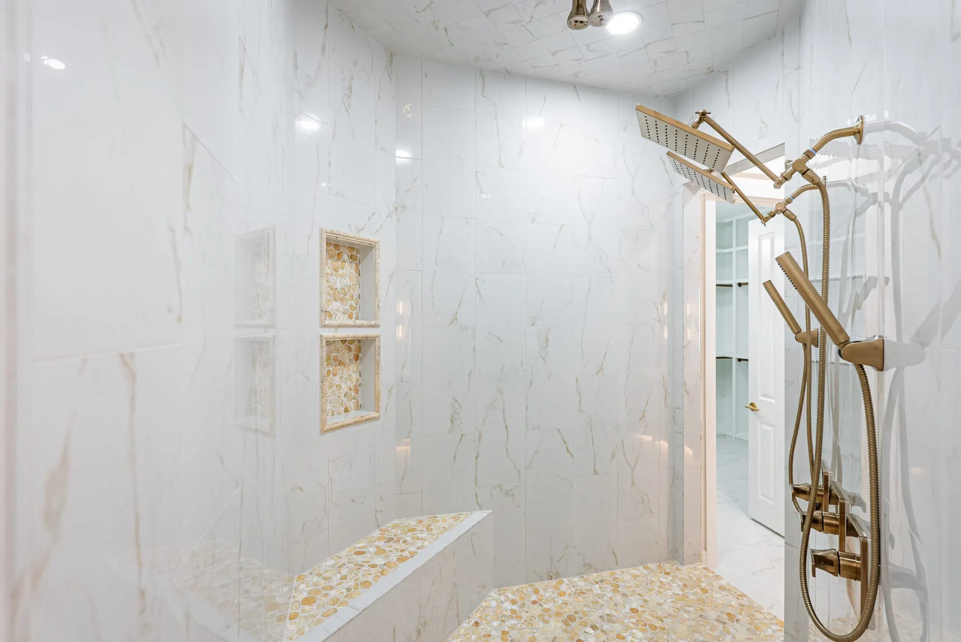 Walk-in shower with gold-veined marble tile and a pebble-mosaic bench at 1607 NW 12th St