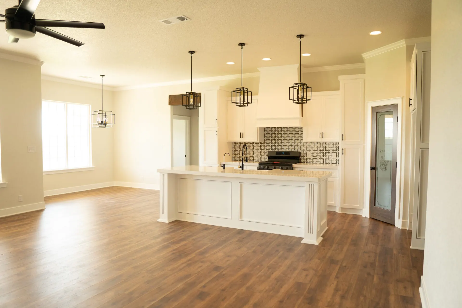 Open kitchen and living area at 1615 NW 12th St in warm light with island seating, hood and geometric tile