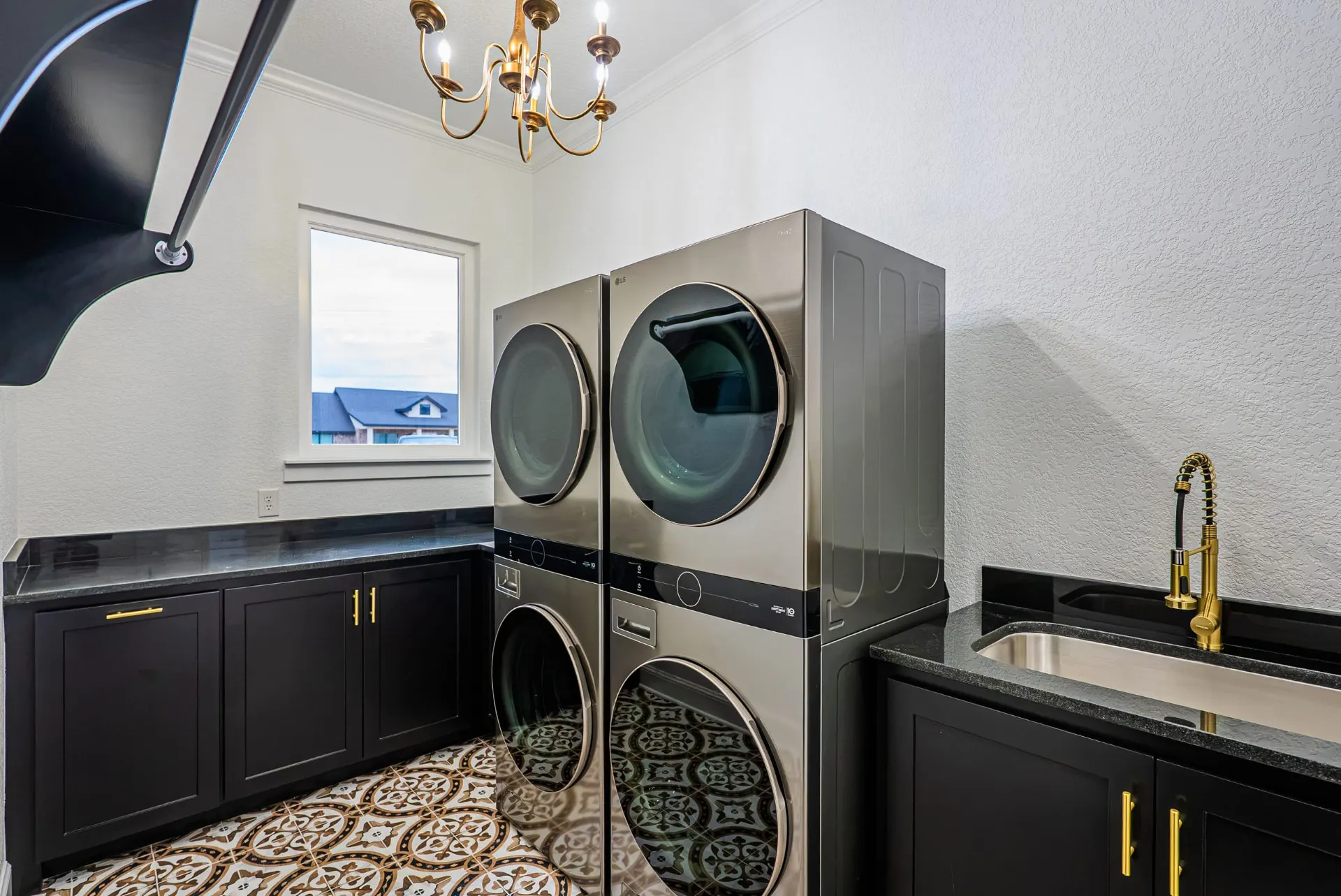 Laundry room with matte black cabinetry, black stone counters and stacked washer-dryer at 1607 NW 12th St
