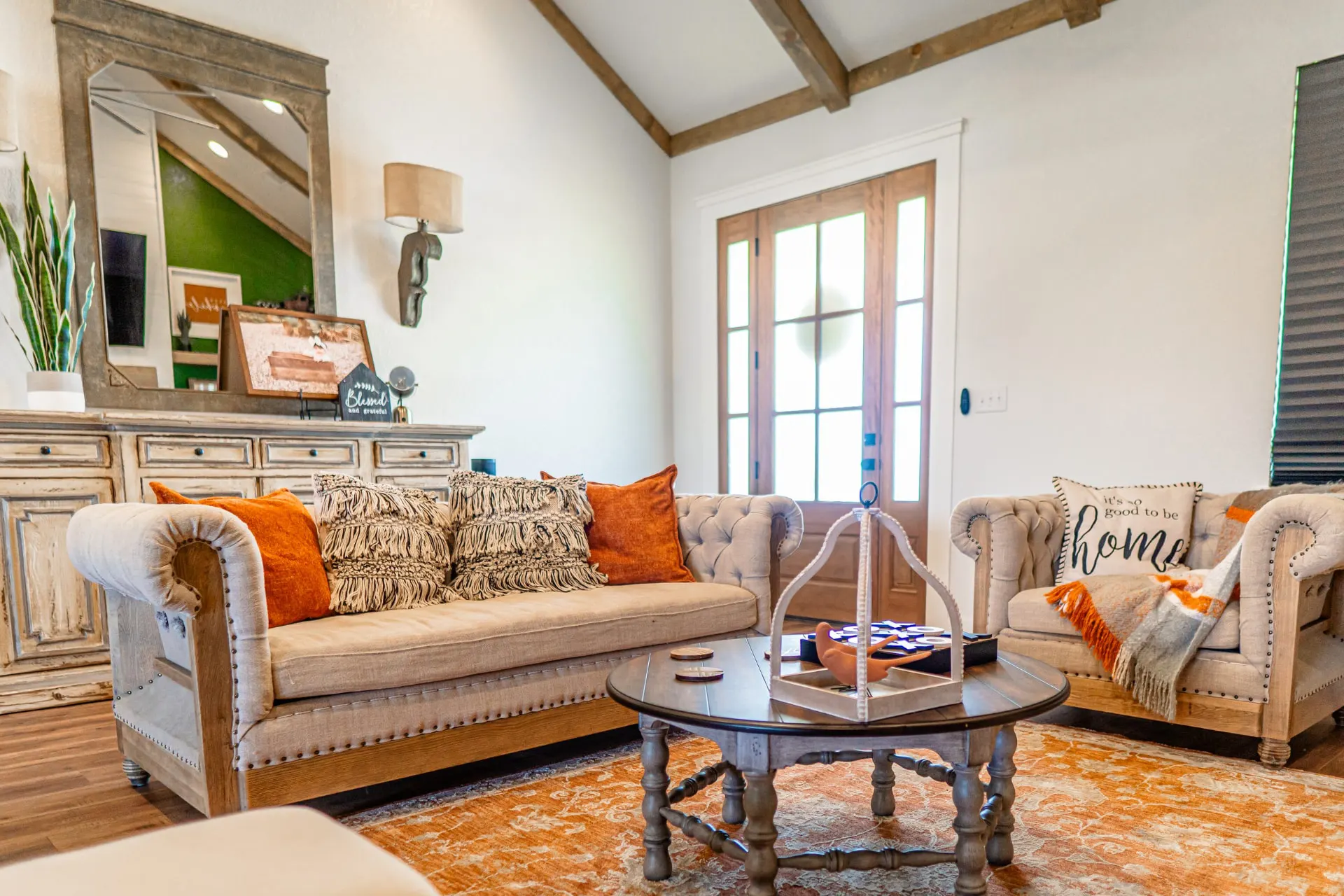 Wide living room view at the K Ave Farmhouse with the tufted sofa, coffee table, front door and green accent wall beyond