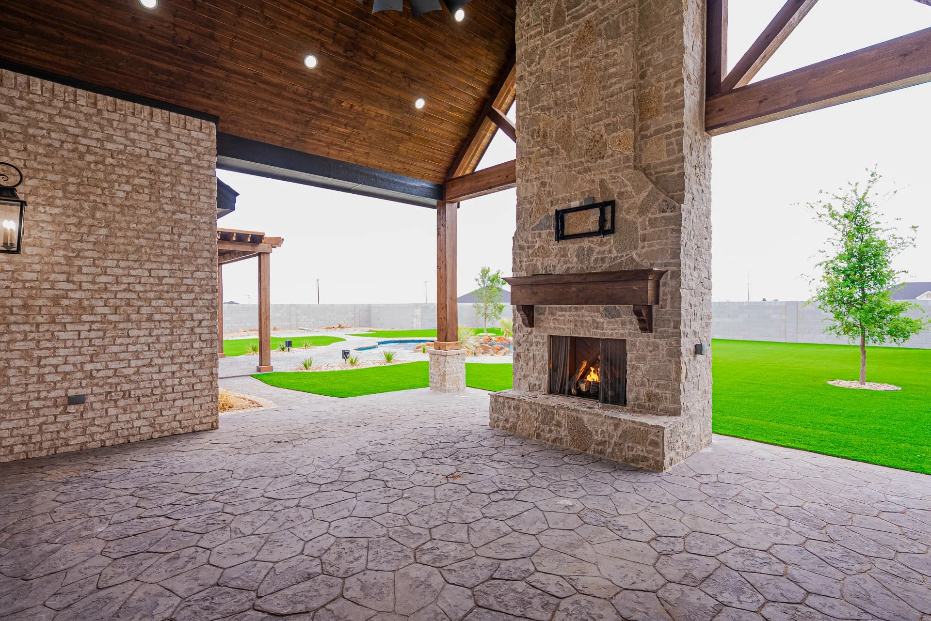 Covered patio with stone fireplace at The Flores Estate