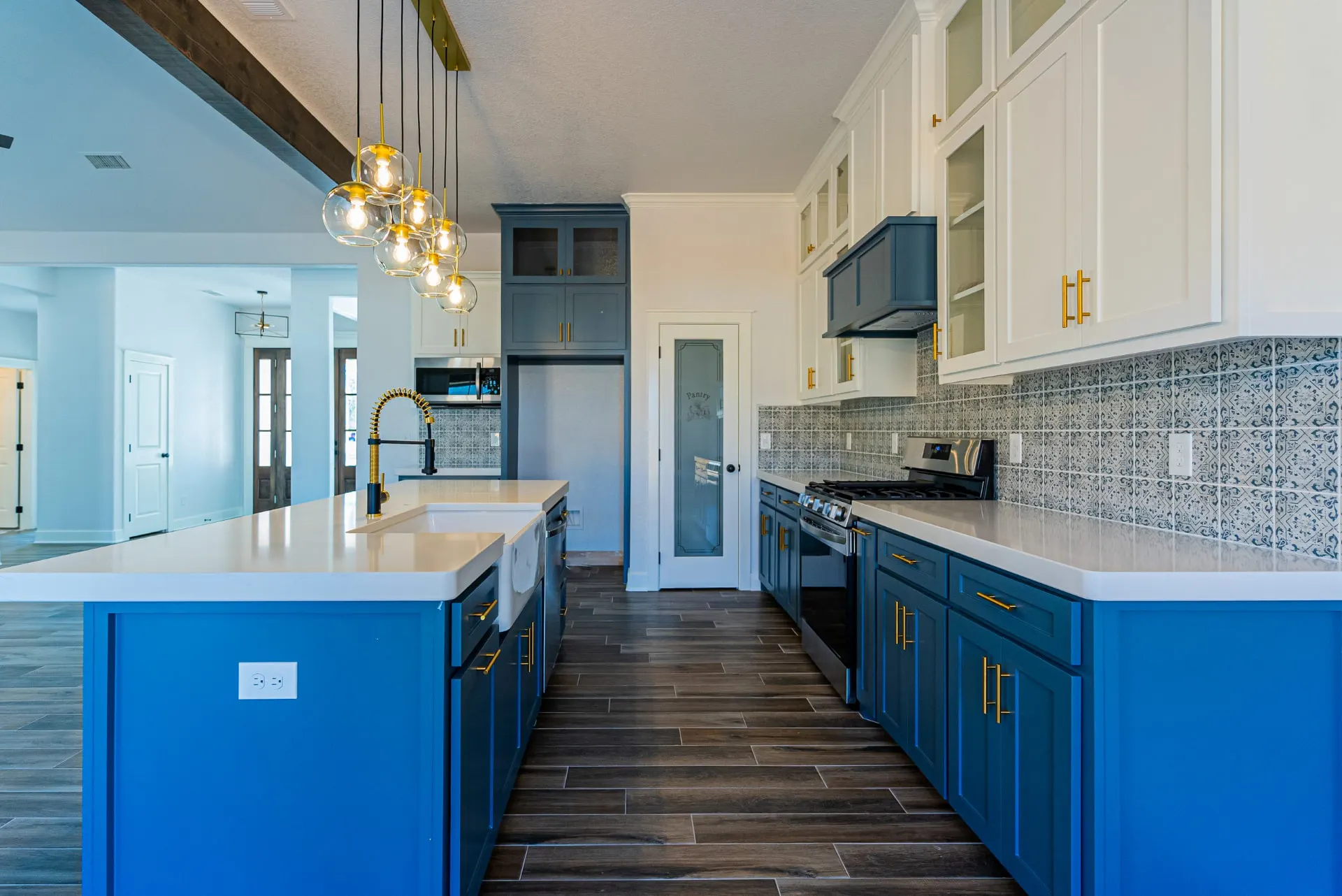 Kitchen aisle at 718 K Ave between the teal island and range wall, with an etched-glass pantry door at the far end