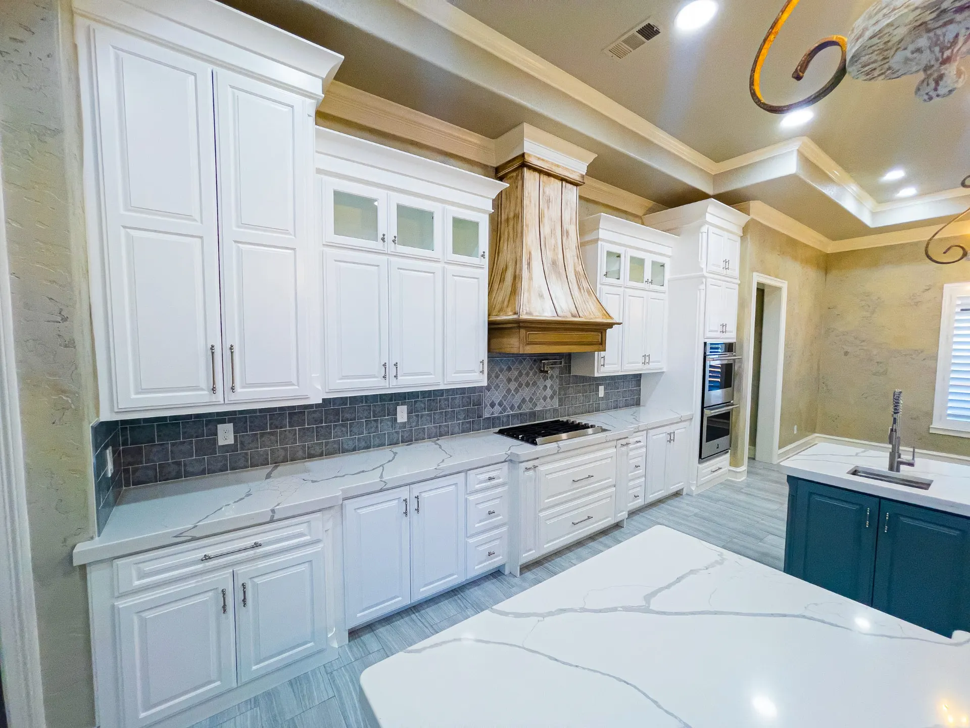White cabinetry run with hand-painted vent hood, double ovens and quartz counters at 1501 NW 12th St