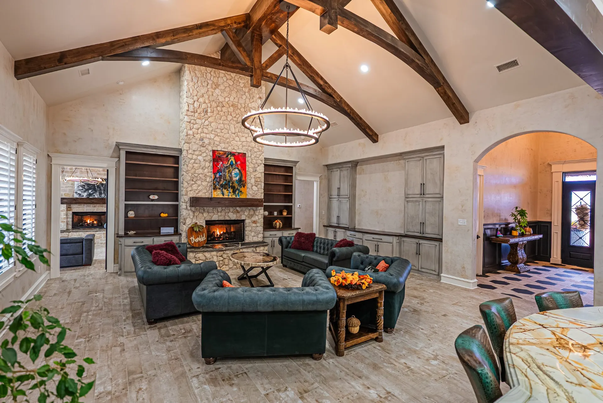 Great room at 5 Prairie Ln with stone fireplace, timber trusses and teal leather seating
