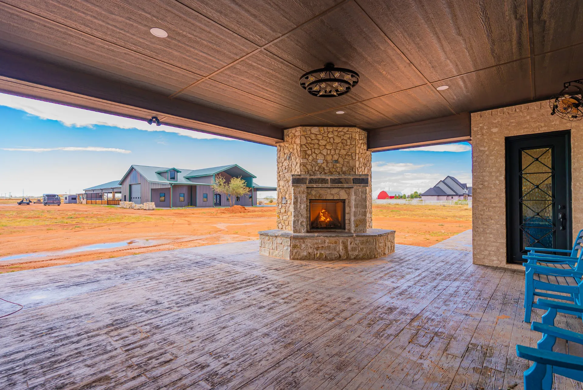 Covered patio at 5 Prairie Ln with stacked-stone fireplace and wood-look concrete floor