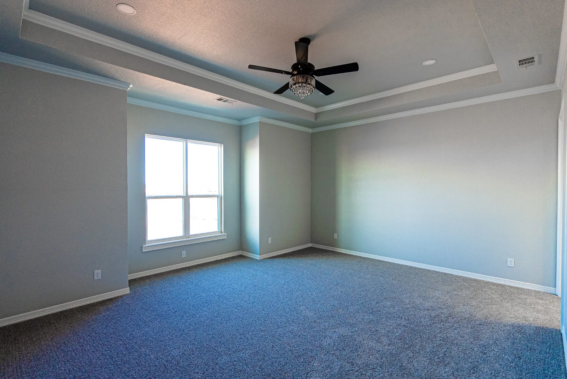 Carpeted bedroom at 1511 NW 12th St with a tray ceiling, crystal-fan fixture and large window