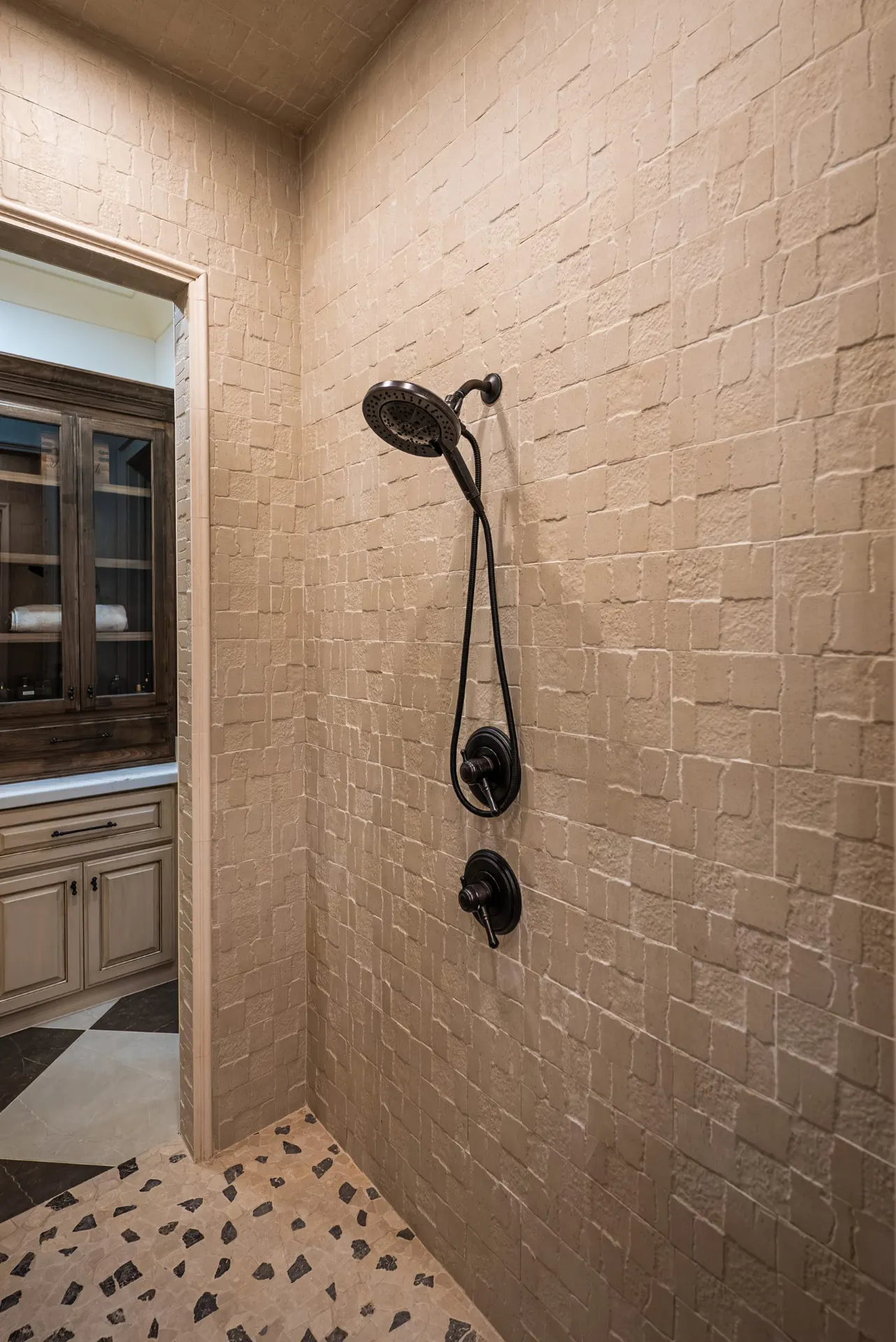 Shower at 1610 NW Eliam Dr with handheld bronze shower head and textured stone walls