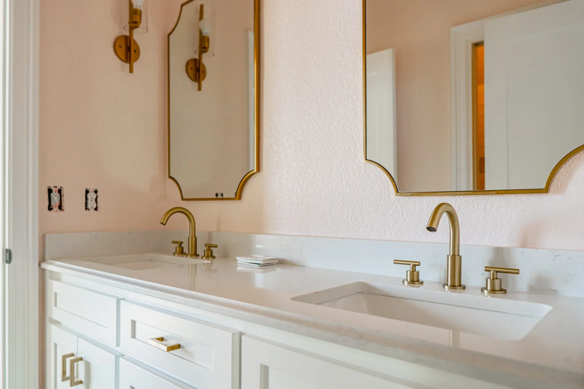 Second angle of the 12th St Home double vanity bath, showing the twin undermount sinks, gold sconces and arched mirrors