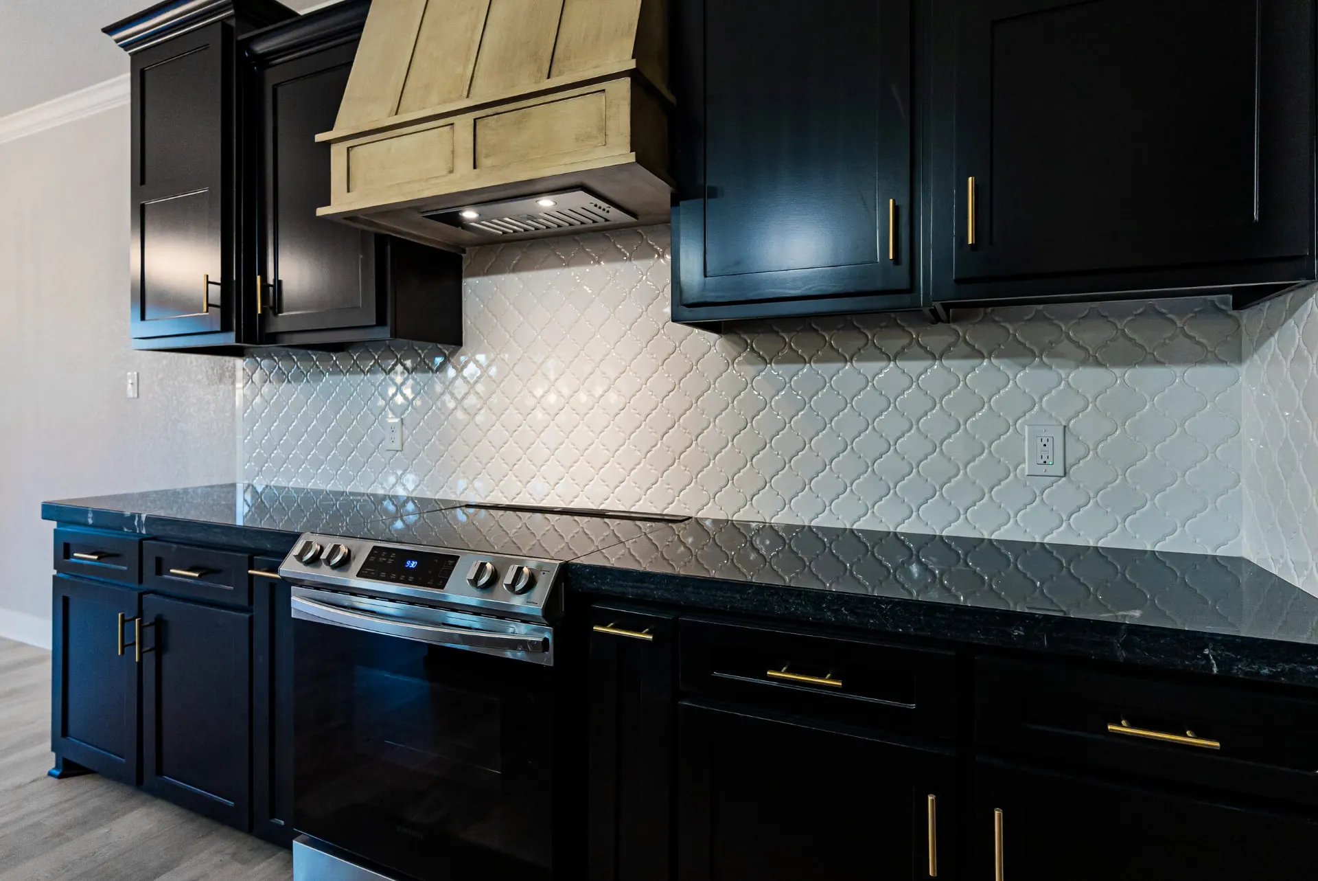Range at 708 K Ave under a stained wood hood, with black marble counters and an arabesque tile backsplash