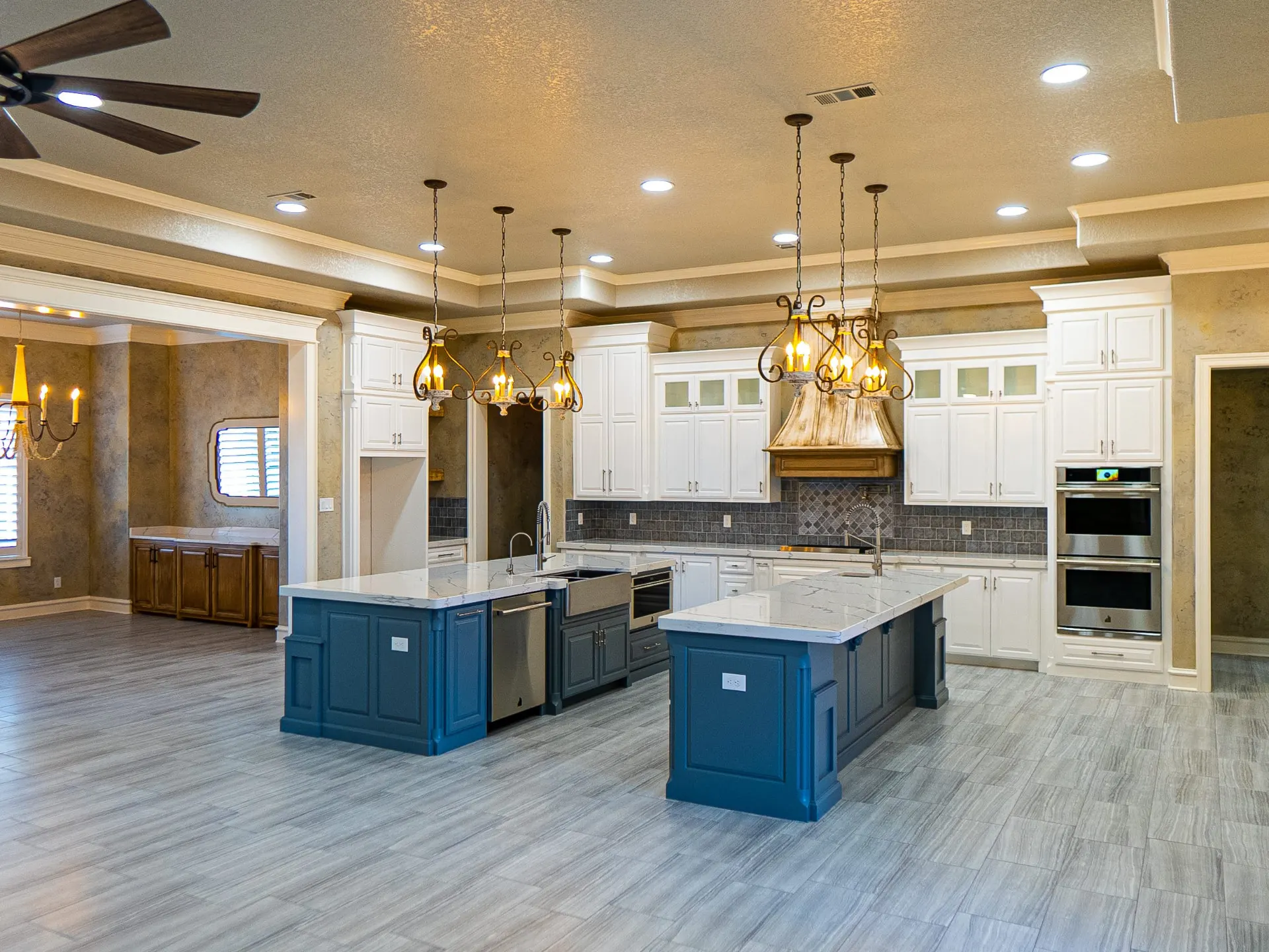Twin teal islands with white marble counters and antiqued brass pendants at 1501 NW 12th St