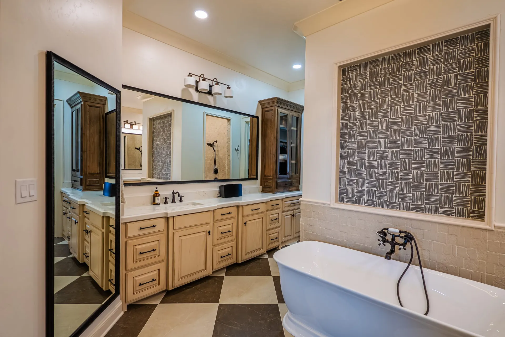 Primary bath at 1610 NW Eliam Dr with freestanding tub, woven-pattern tile panel and checkerboard stone floor