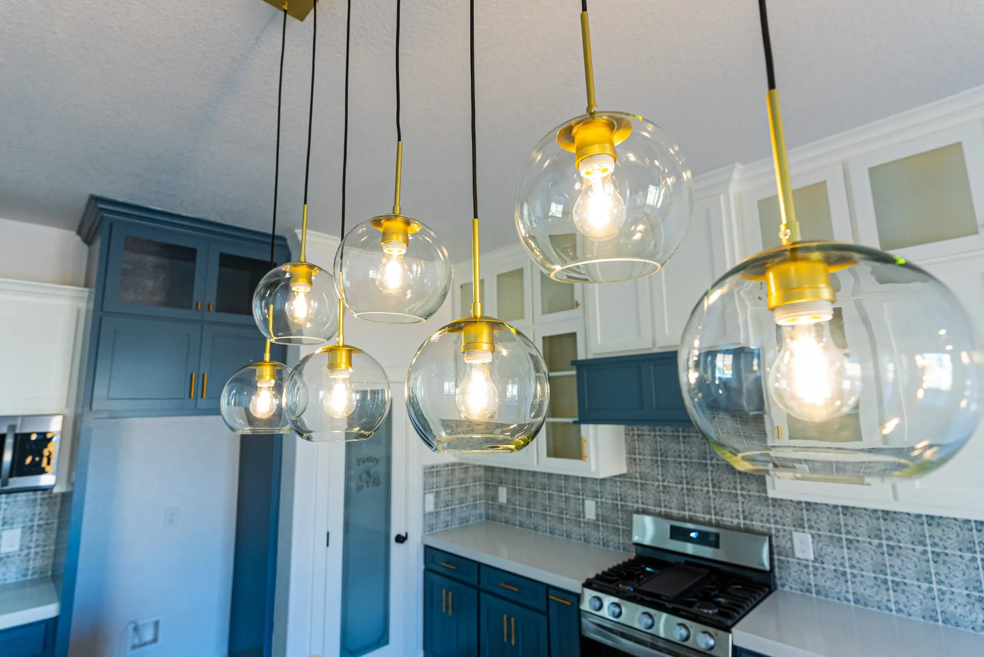 Glass globe pendants with brass fittings over the kitchen island at 718 K Ave