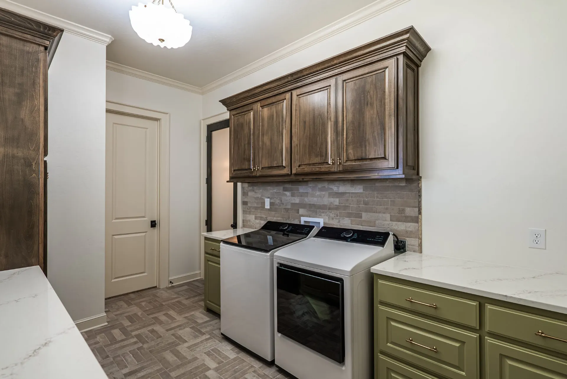 Laundry room at 1610 NW Eliam Dr with sage green base cabinets, dark wood uppers and white quartz counters
