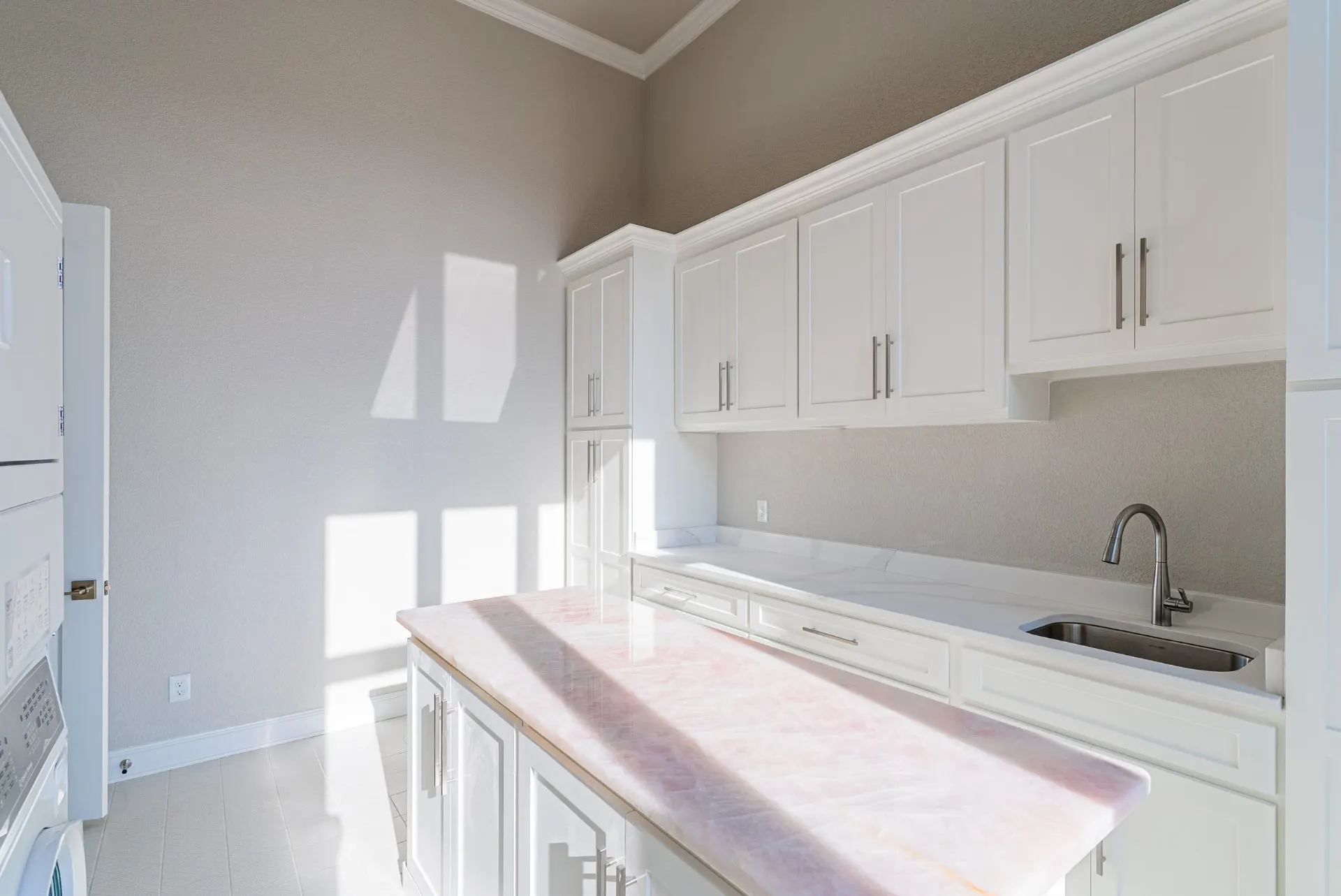 Laundry room with a rose quartz island and white shaker cabinetry at 27 Santiago Mission Dr
