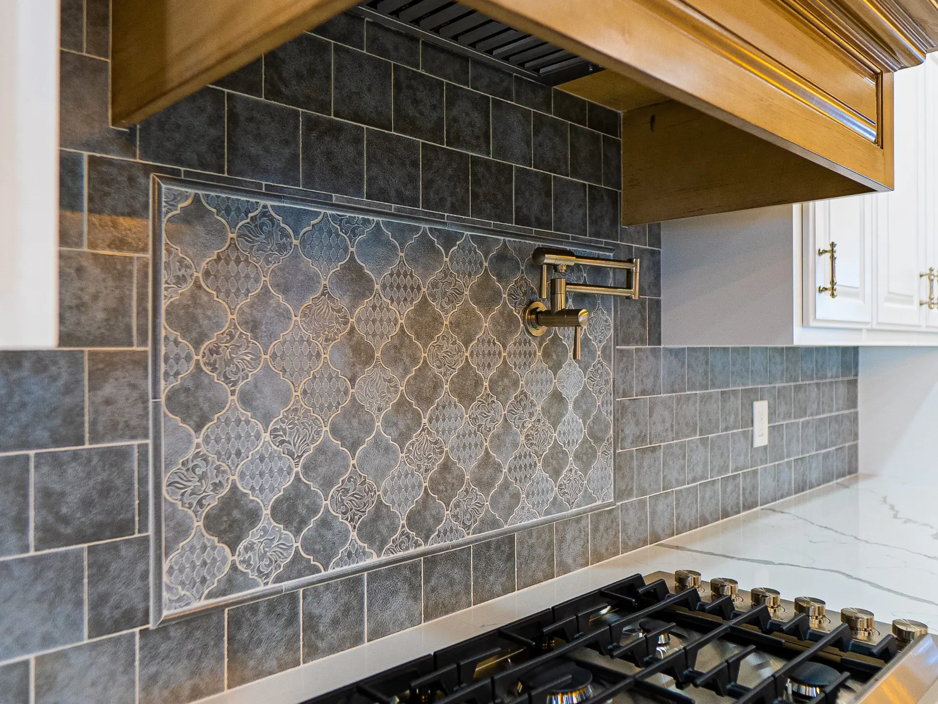 Arabesque tile backsplash with a brass pot filler over the range at 1501 NW 12th St