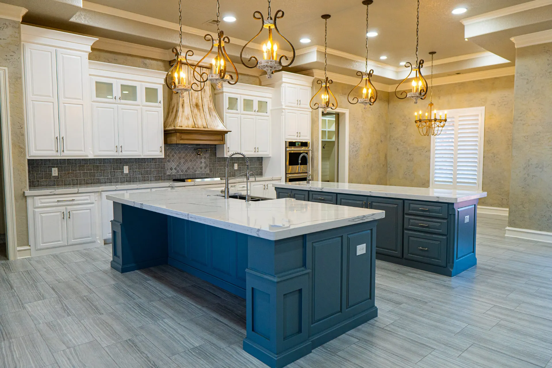 Twin teal islands beneath antiqued wrought-iron pendants at 1501 NW 12th St