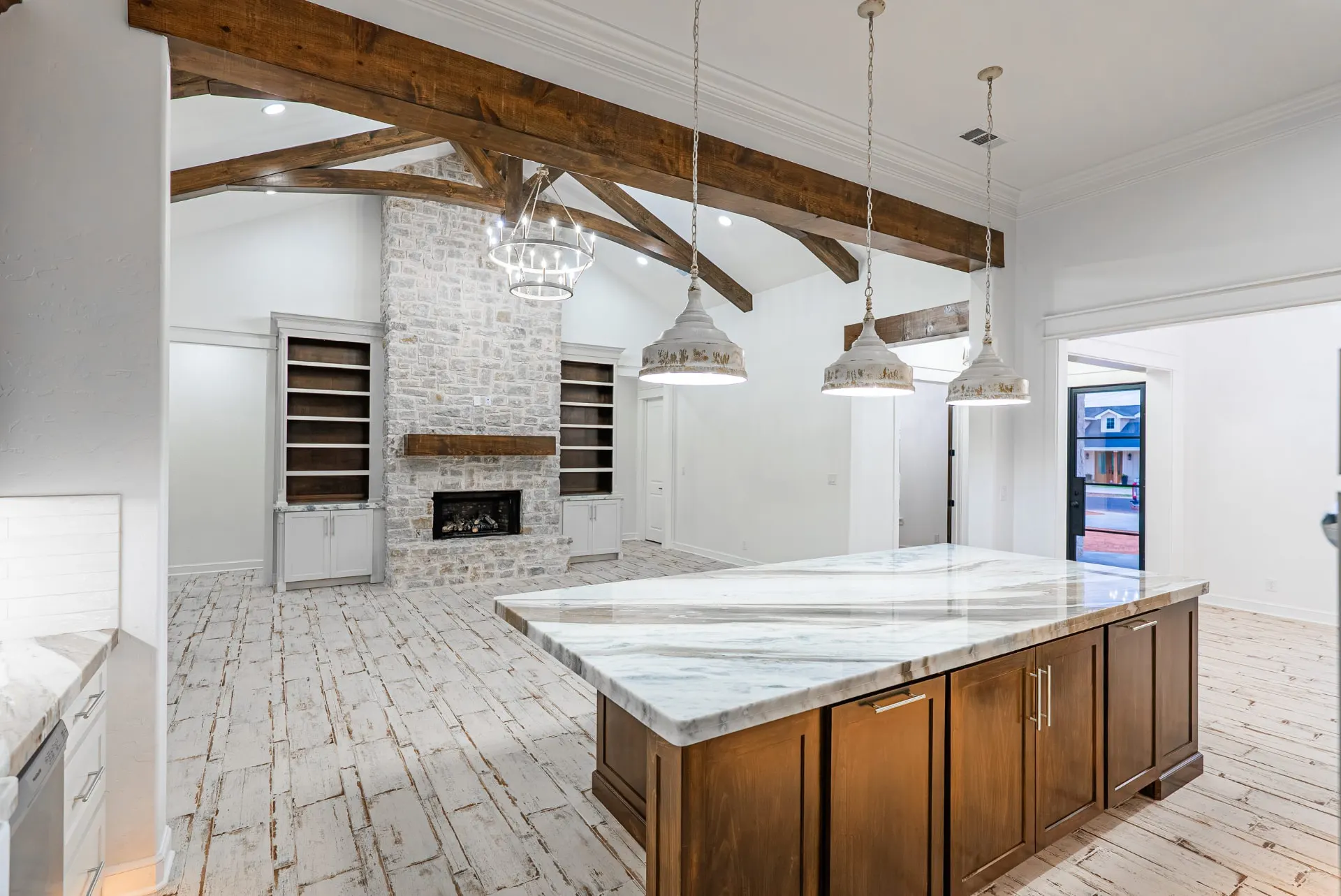 Great room at 1607 NW 12th St with stone fireplace, timber trusses and ring chandelier
