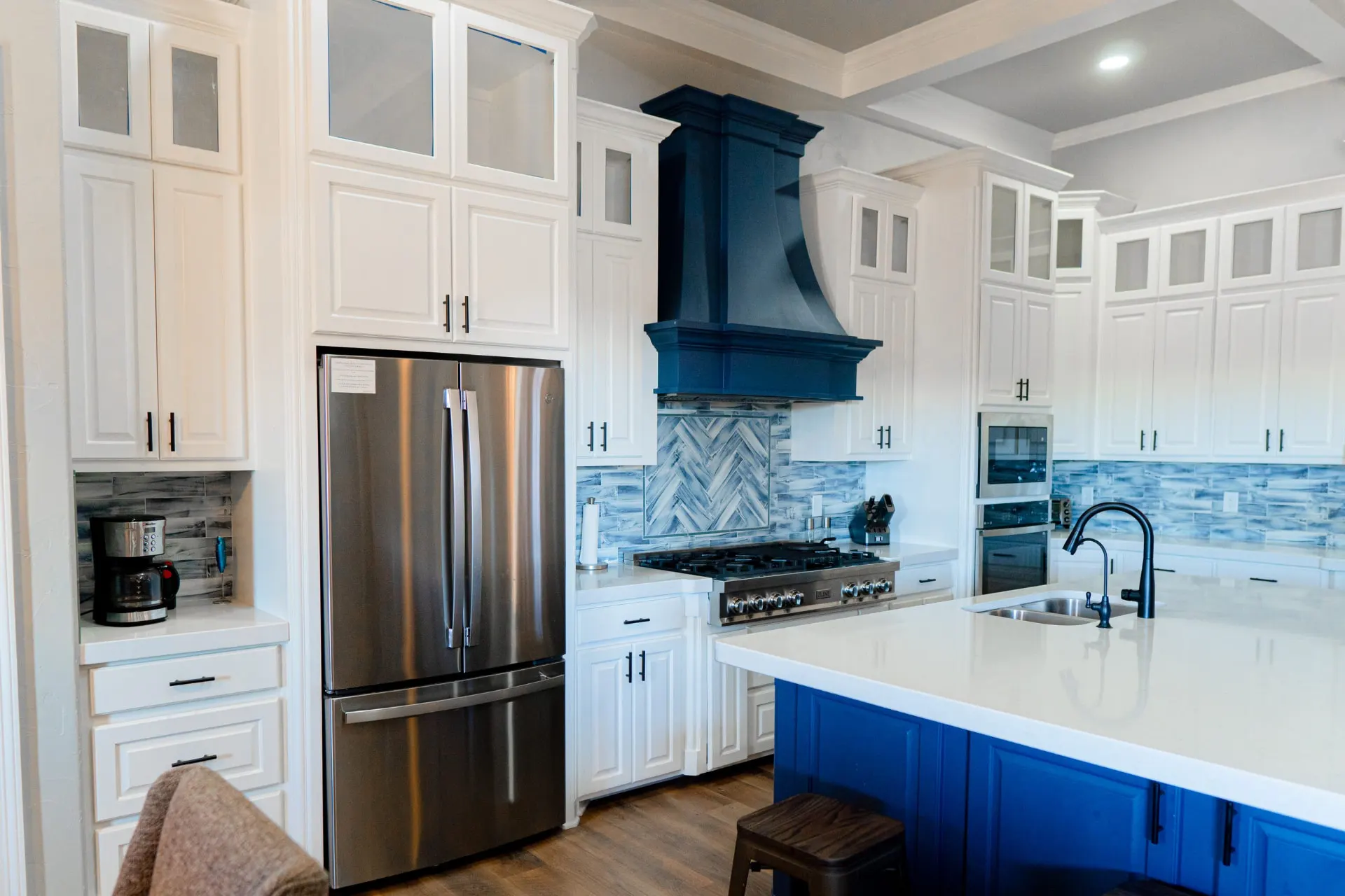 Kitchen at 8821 Shawn Dr seen from above, with a stainless French-door refrigerator, a commercial gas range under the navy hood, and an island with an undermount sink and matte black faucet