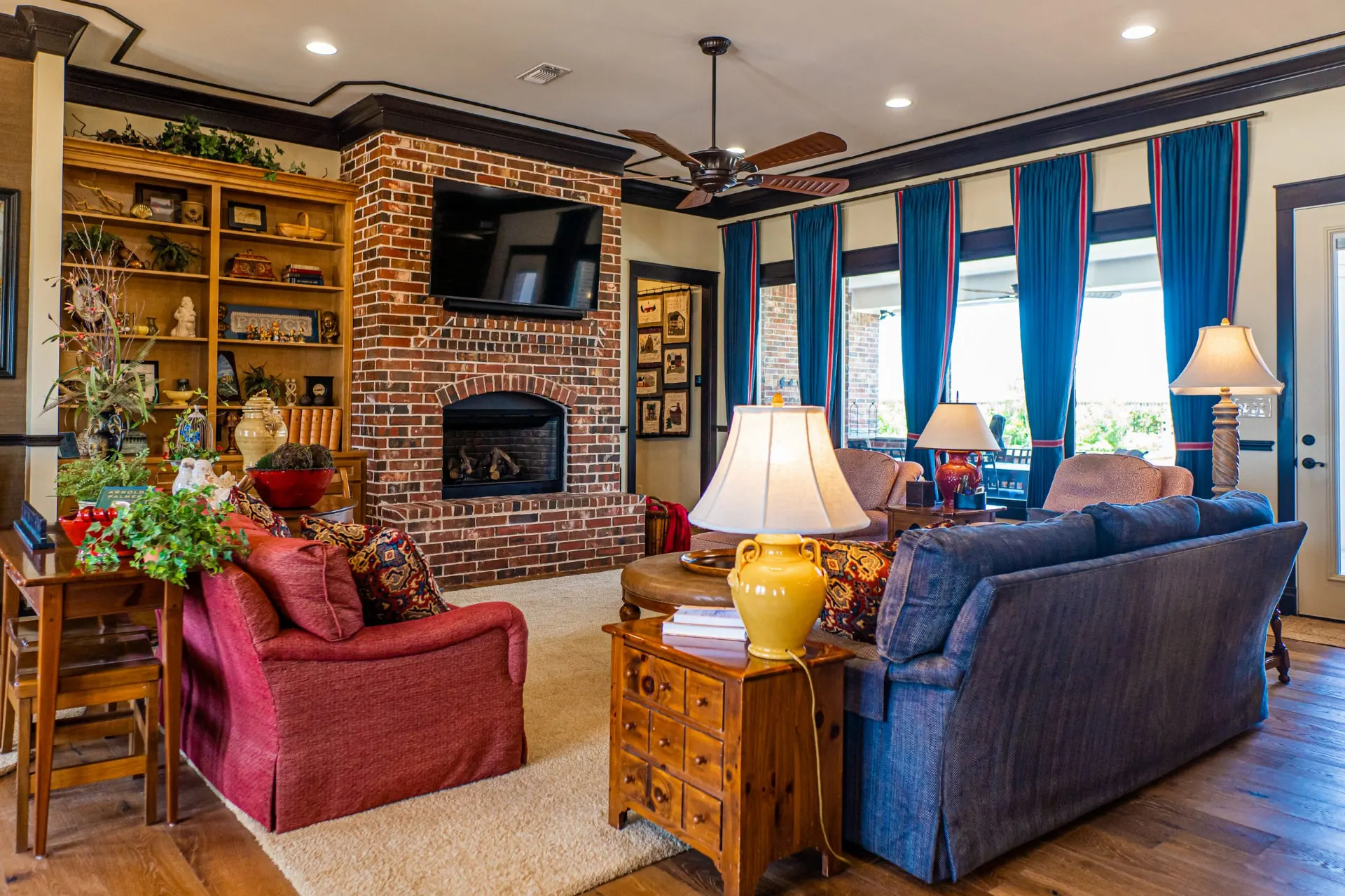 Living room at the Wraparound Porch Home with a brick fireplace, built-in shelving and a navy sofa, beside a white exterior door