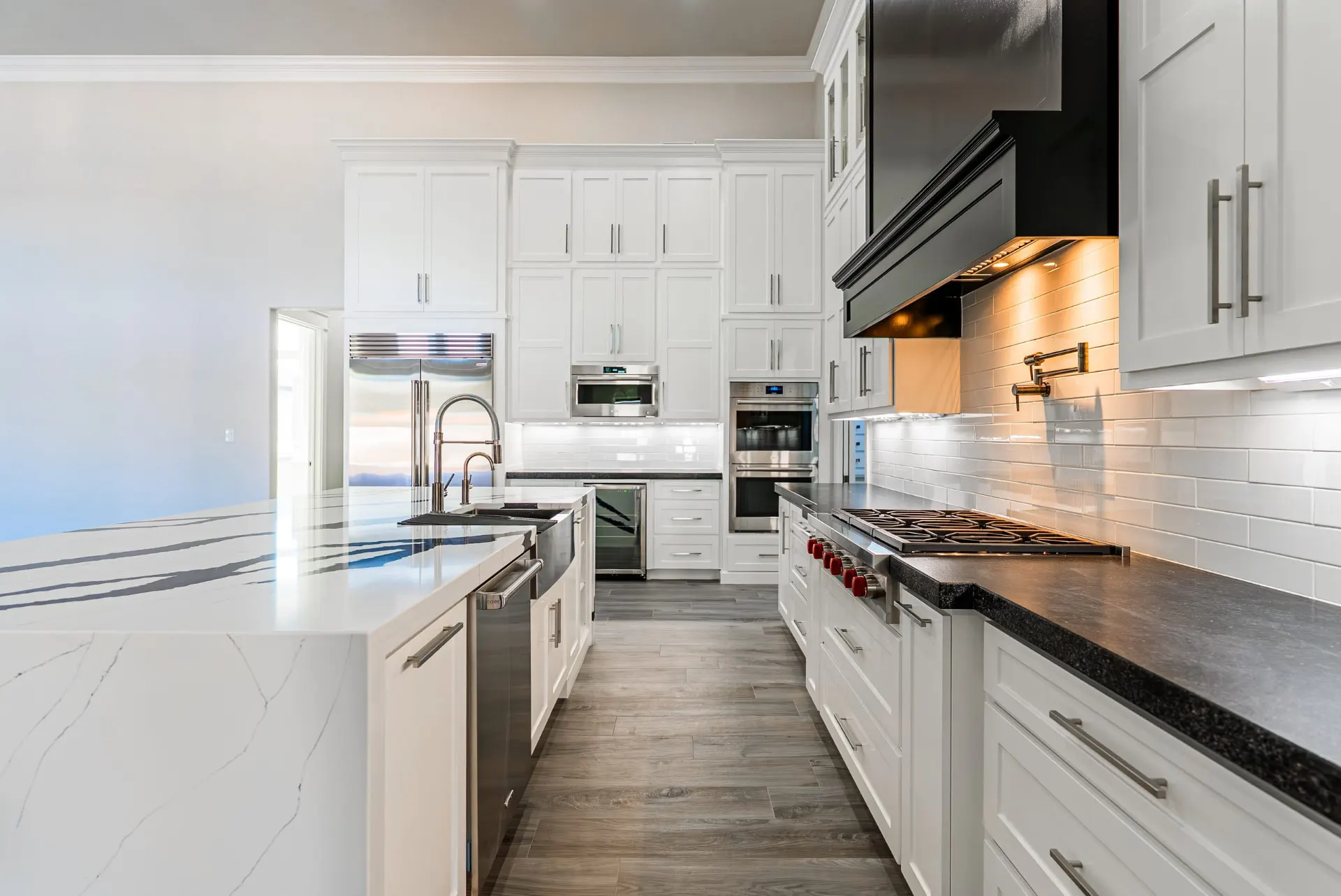 Galley view of the 27 Santiago Mission Dr kitchen with a Wolf rangetop, pot filler and lit subway-tile backsplash
