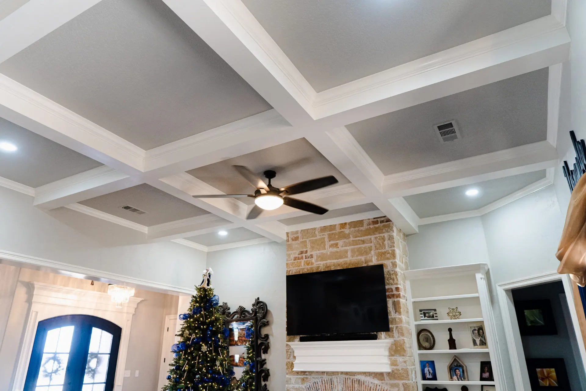 Coffered ceiling detail at 8821 Shawn Dr with white beams over grey panels above the stone fireplace
