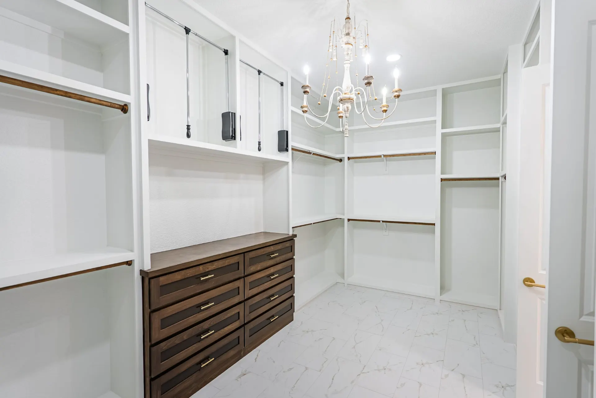 Walk-in closet with pull-down rods, stained dresser and a whitewashed chandelier at 1607 NW 12th St