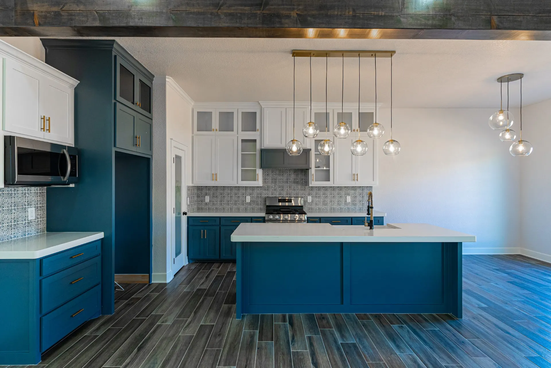Kitchen at 718 K Ave with teal lower cabinets, white glass-front uppers, patterned blue backsplash and a cluster of glass globe pendants over the island