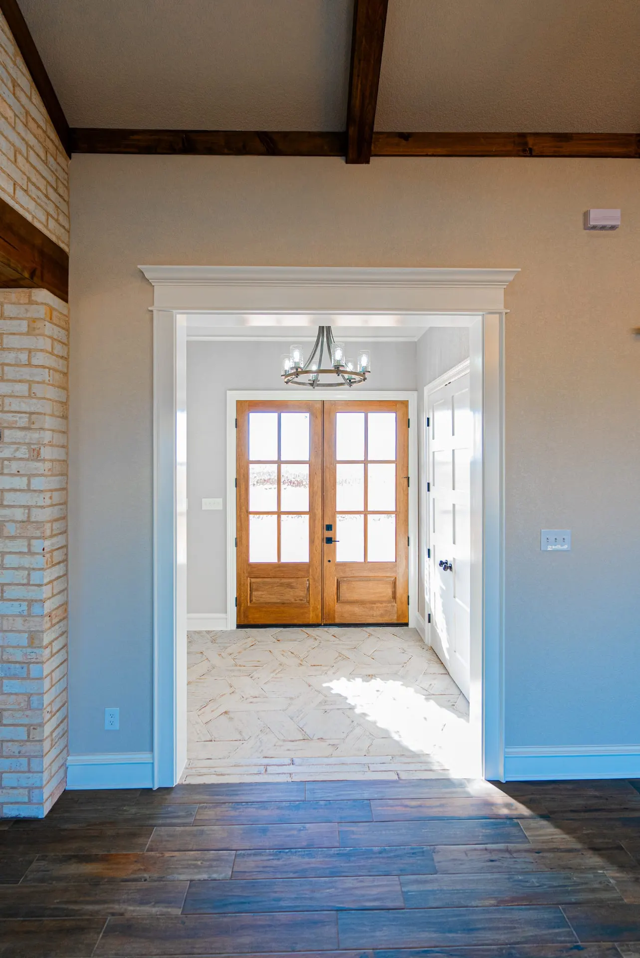 Entry at 1602 NW 12th St with wood-and-glass double doors, herringbone tile floor and beamed ceiling