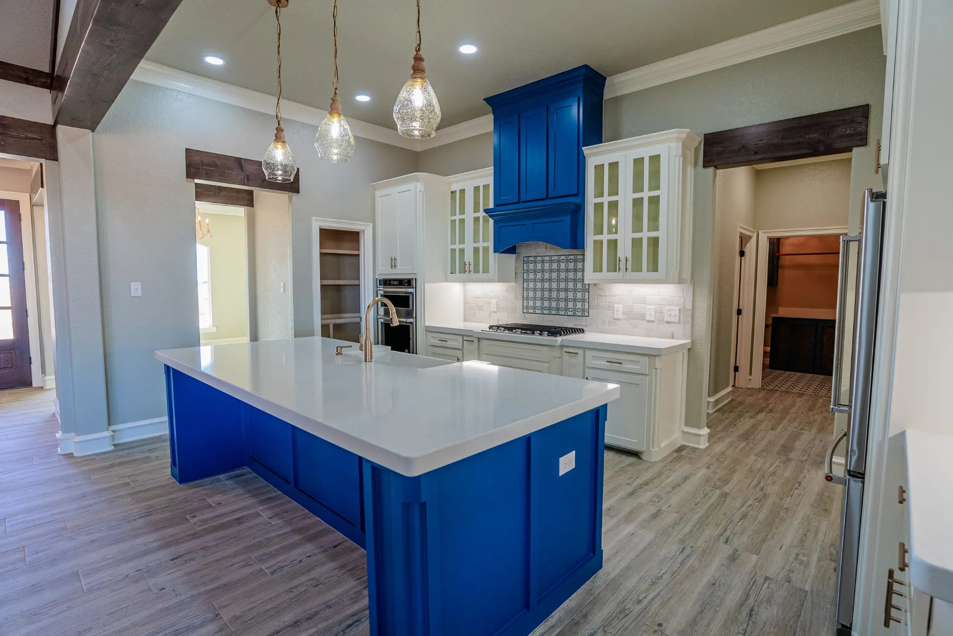 Angled view of the Eliam St Home kitchen showing the cobalt island, brass faucet, patterned backsplash and pantry doorway