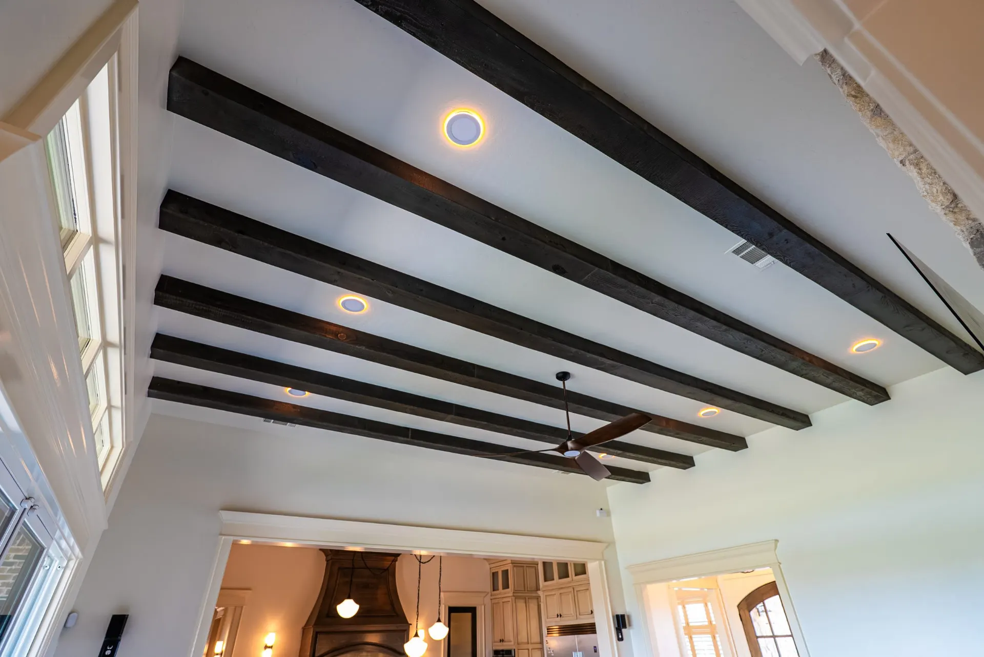 Vaulted ceiling with dark stained beams and a wood-blade fan in the great room at 1610 NW Eliam Dr
